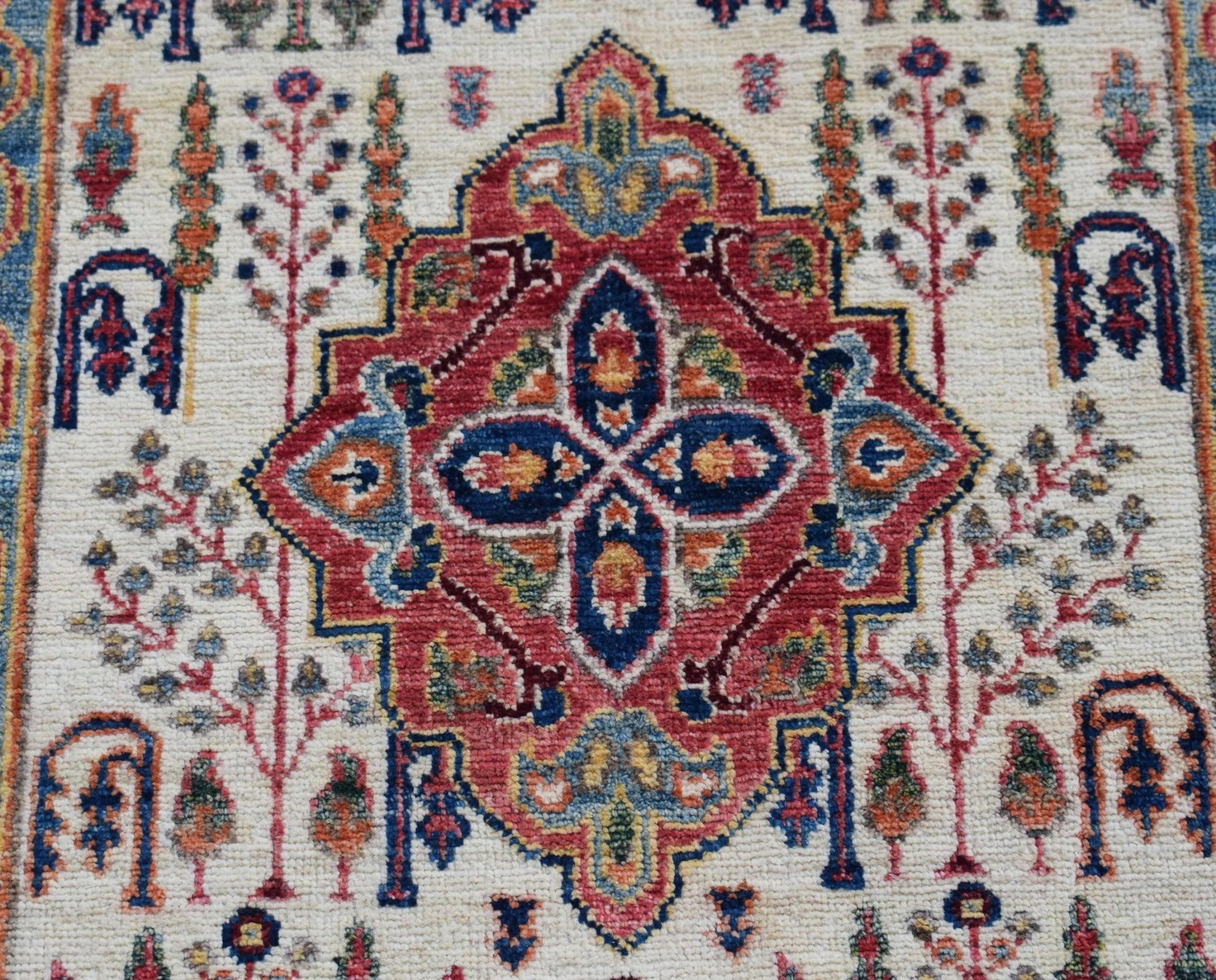 A handwoven Afghan Chobi rug featuring a central red medallion with intricate floral motifs.