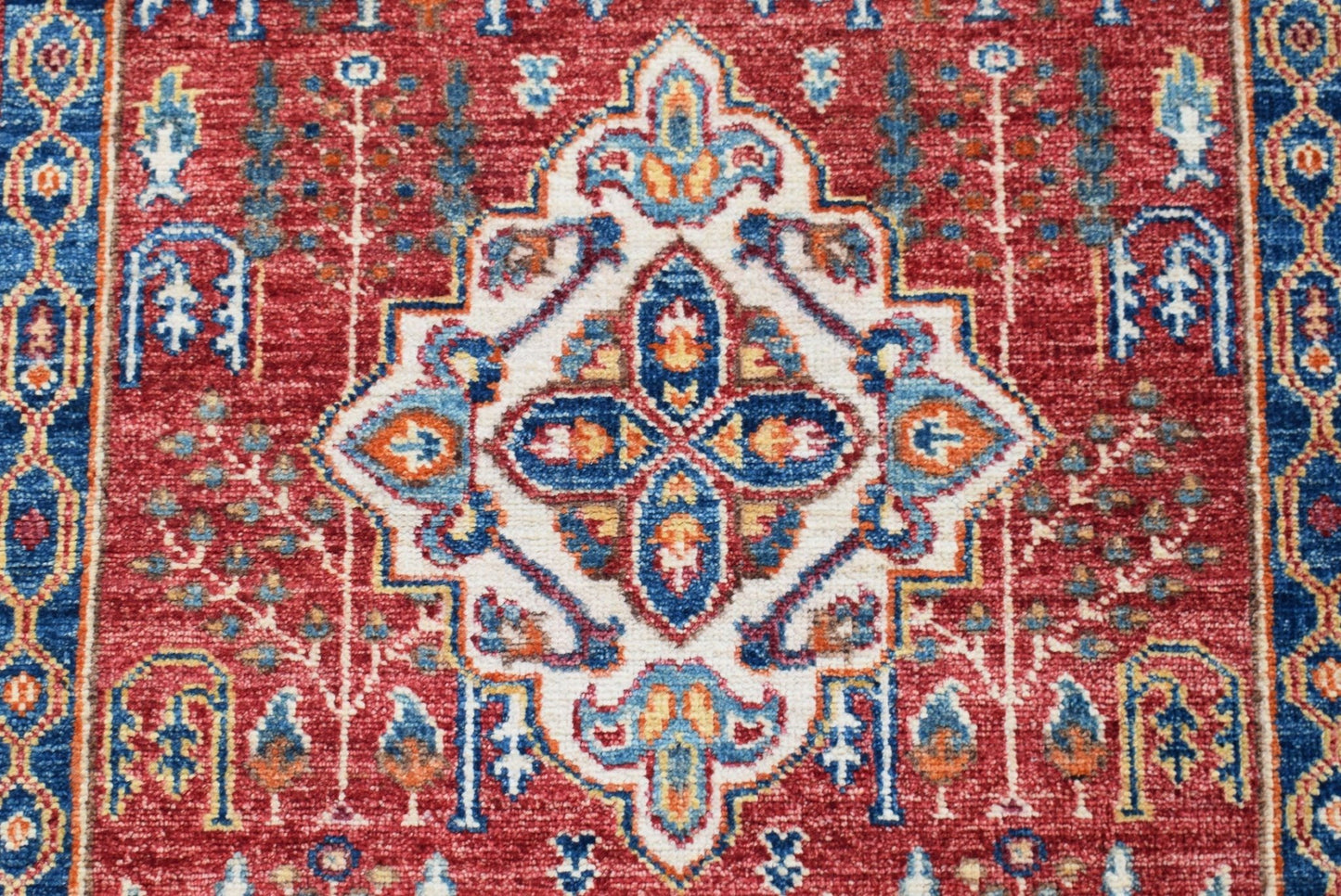 A handmade Afghan Chobi rug featuring a traditional Heriz medallion pattern in red and blue.