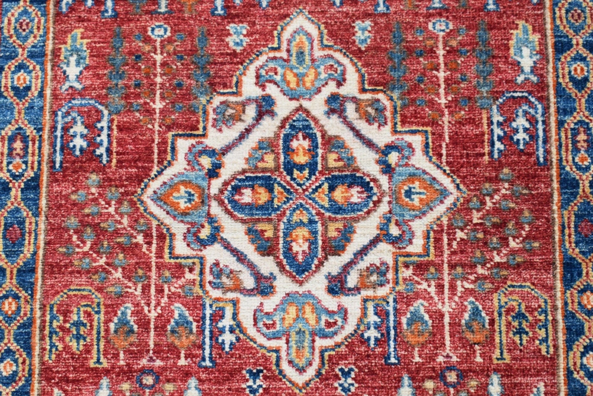 A handmade Afghan Chobi rug featuring a traditional Heriz medallion pattern in red and blue.