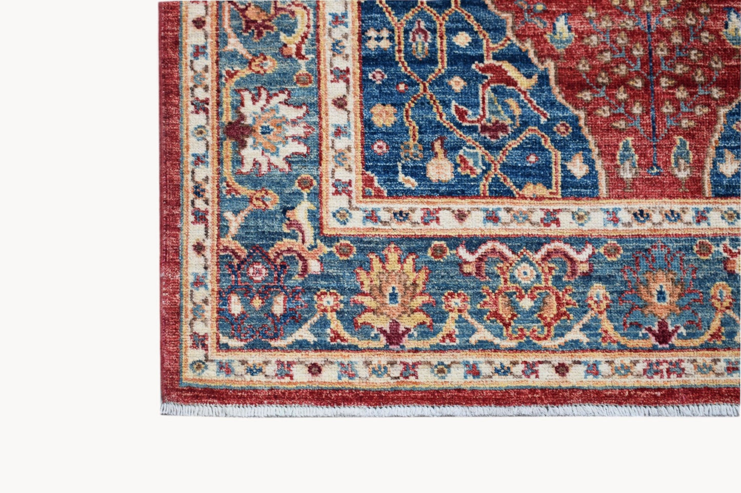 A corner view of a handmade Afghan Chobi rug featuring a traditional Heriz pattern in red and blue.