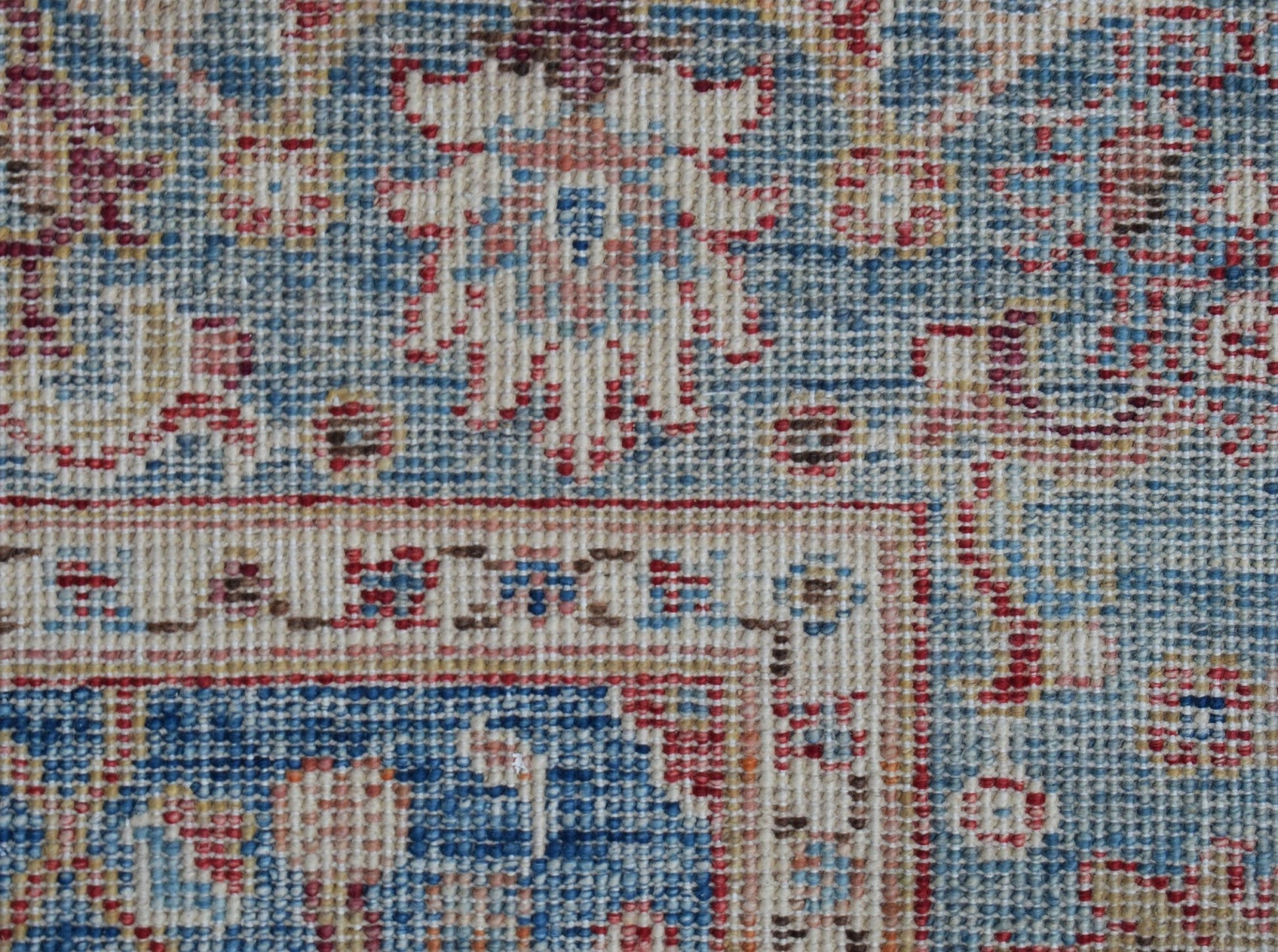 A close-up of a handwoven Afghan Chobi rug featuring intricate floral patterns in blue and red.
