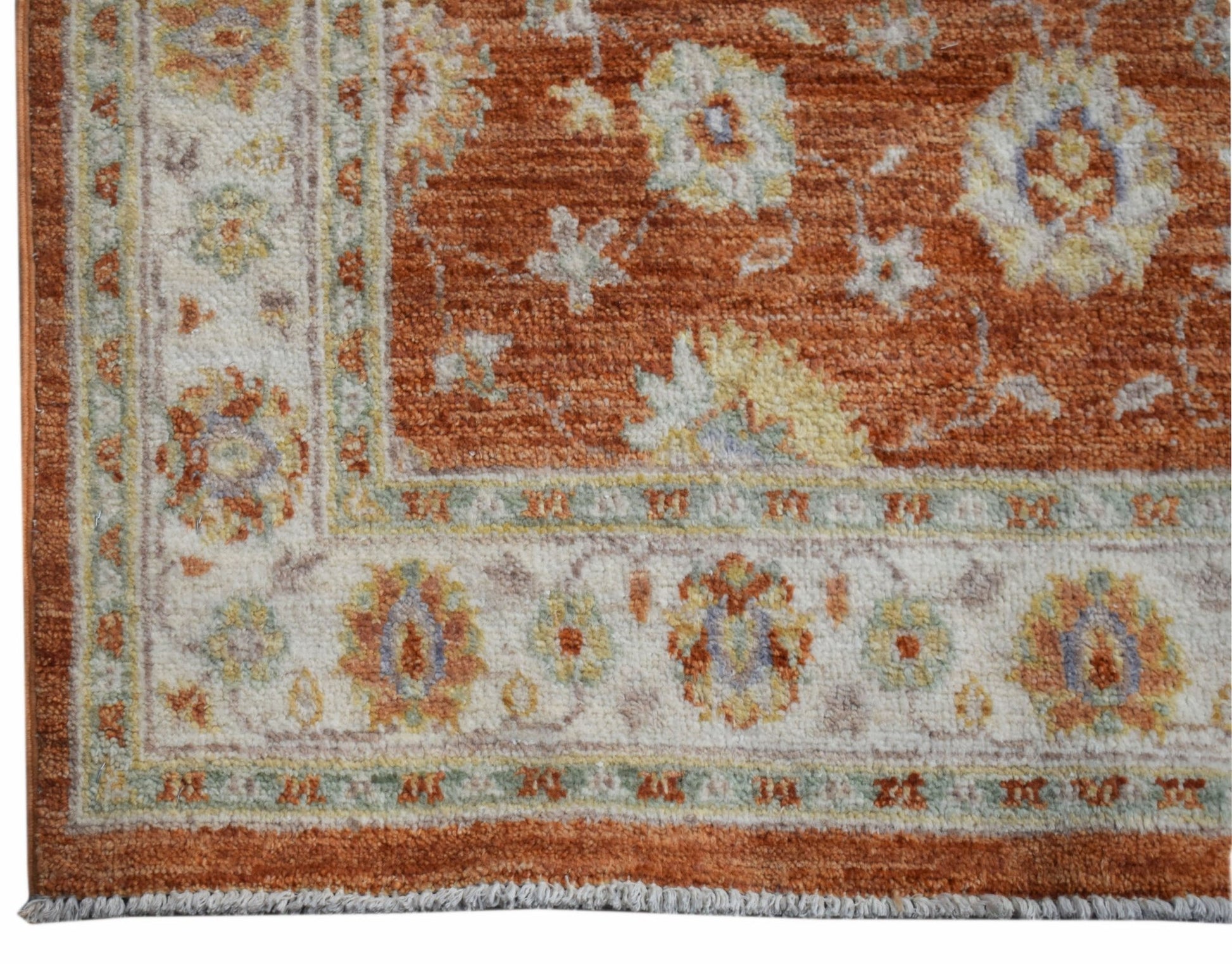 A handmade Afghan Chobi rug featuring a floral pattern in rust, cream, and soft blue tones.