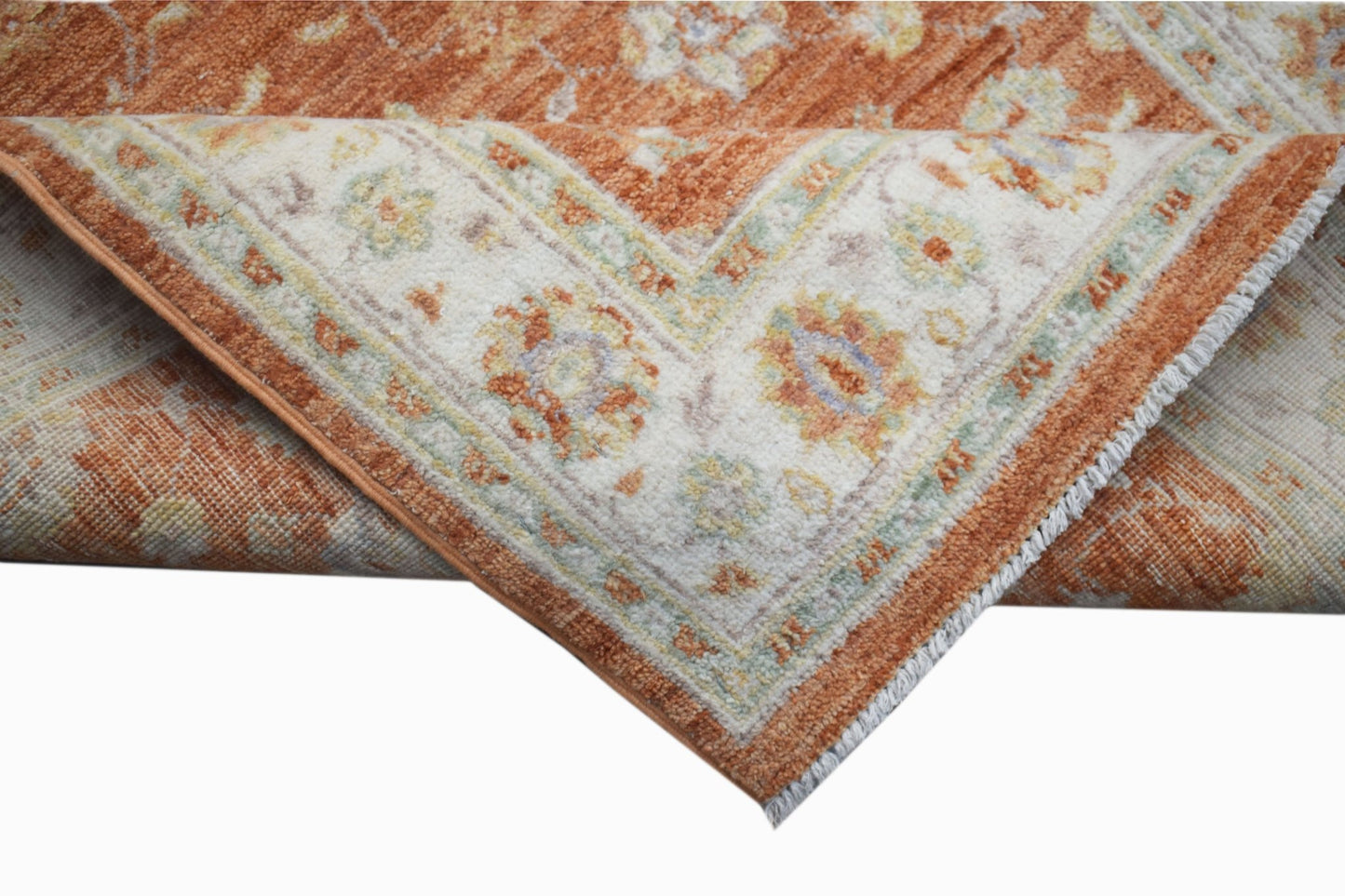 A folded Afghan Chobi rug featuring a traditional floral pattern in shades of orange and cream.