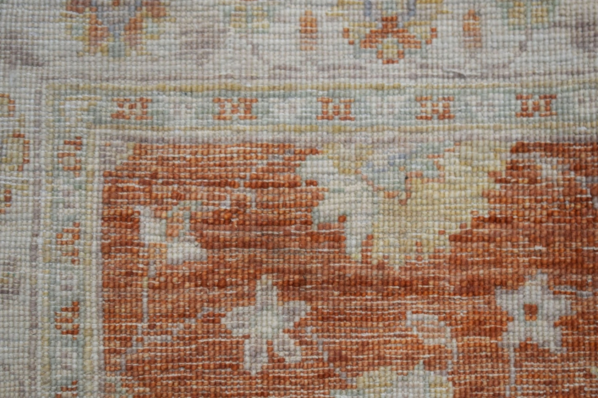 A close-up of a handwoven Afghan Chobi rug featuring earthy orange and cream floral patterns.