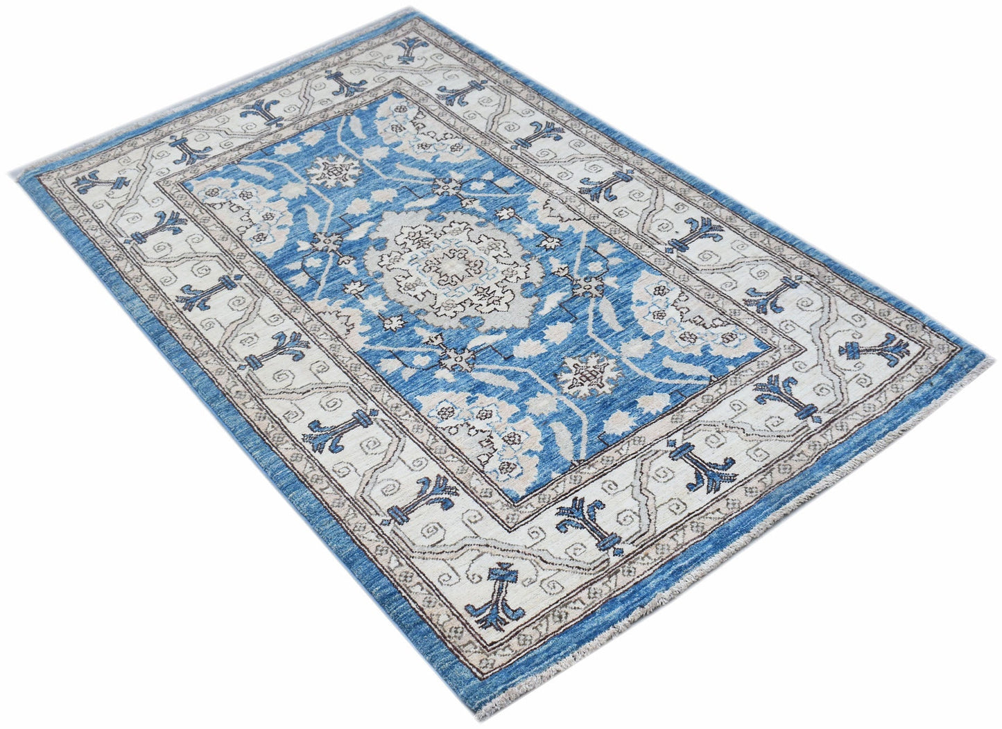 A rectangular Afghan Chobi rug featuring a blue field with a central medallion and floral motifs.