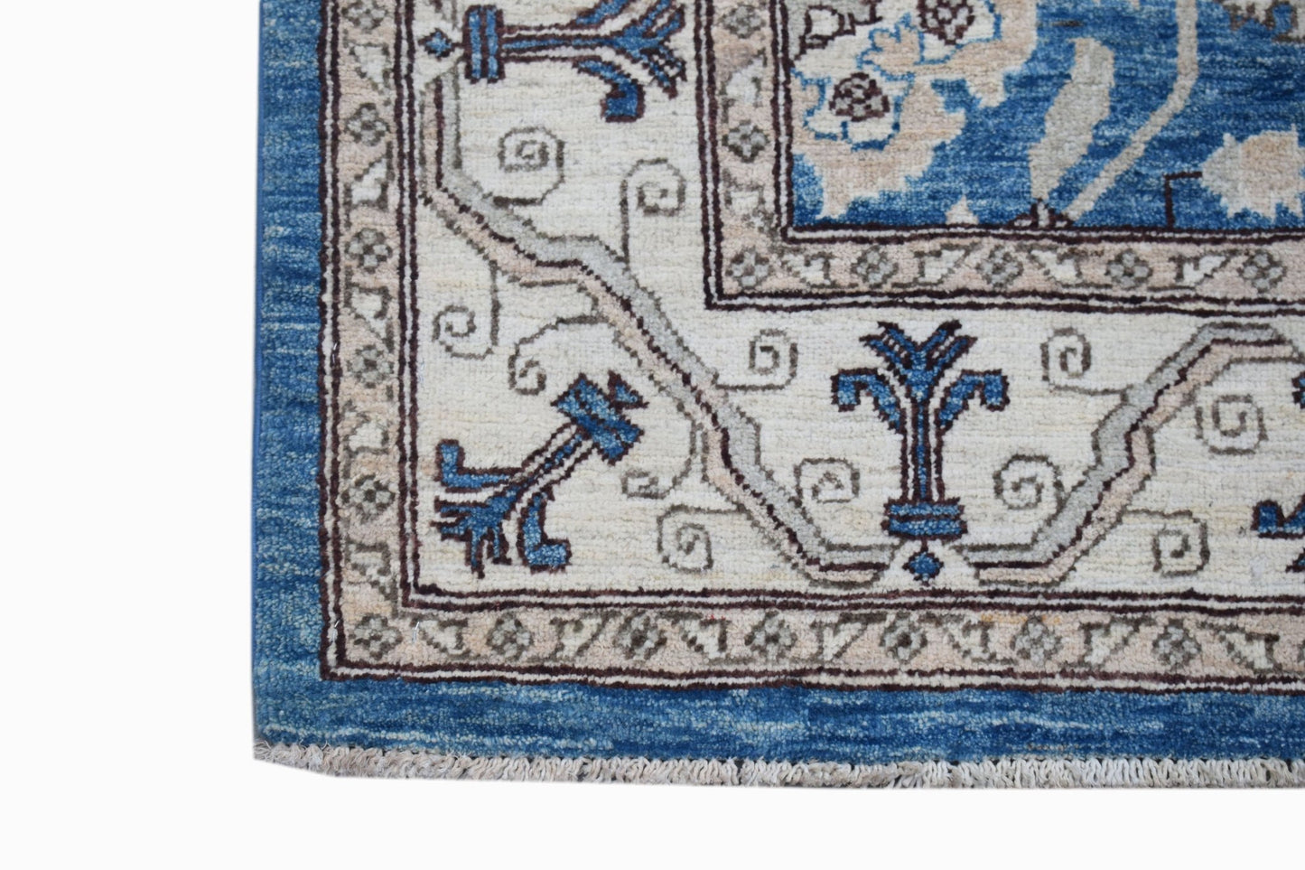 A corner view of a handwoven Afghan Chobi rug featuring blue and cream floral patterns.