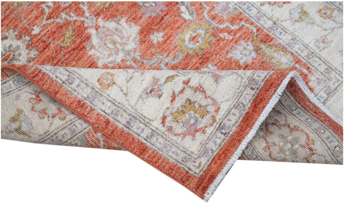 A handwoven Afghan Chobi rug featuring a traditional floral pattern in orange and cream tones.