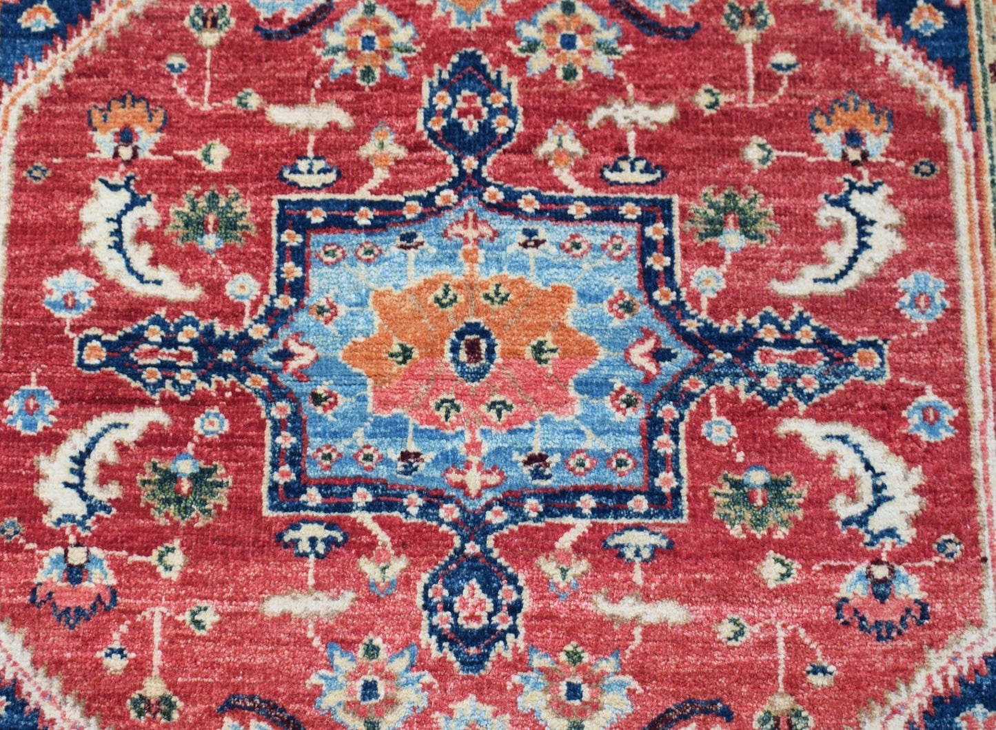 A handmade Afghan Chobi rug featuring a traditional Heriz pattern in red, blue, and orange tones.