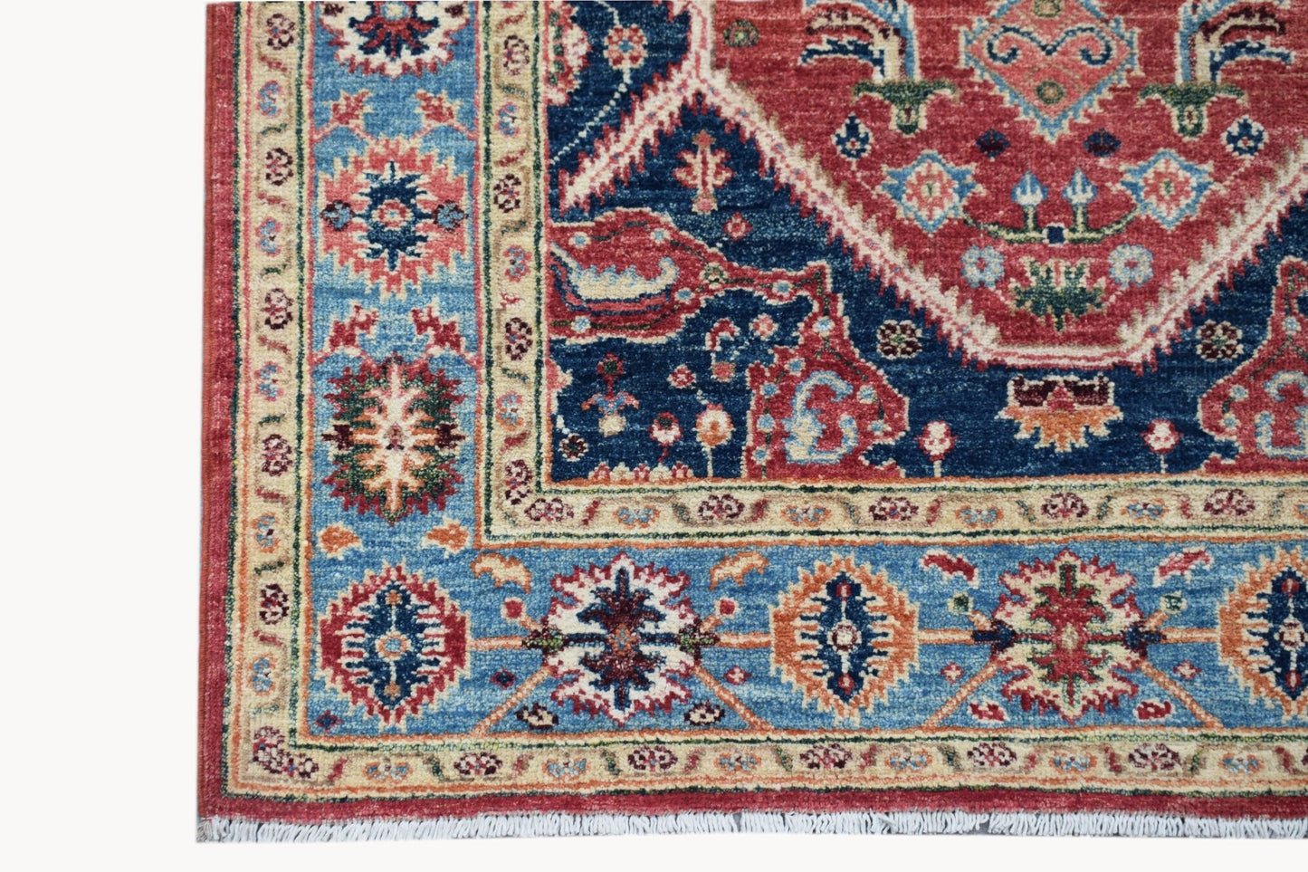 A handmade Afghan Chobi rug featuring a traditional Heriz pattern in red, blue, and cream tones.