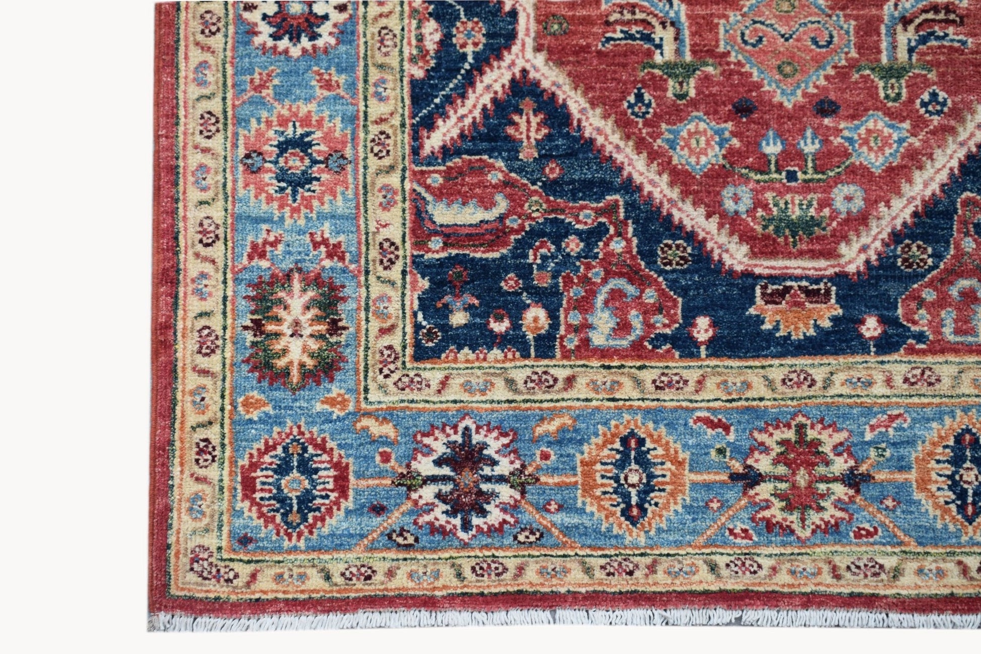 A handmade Afghan Chobi rug featuring a traditional Heriz pattern in red, blue, and cream tones.