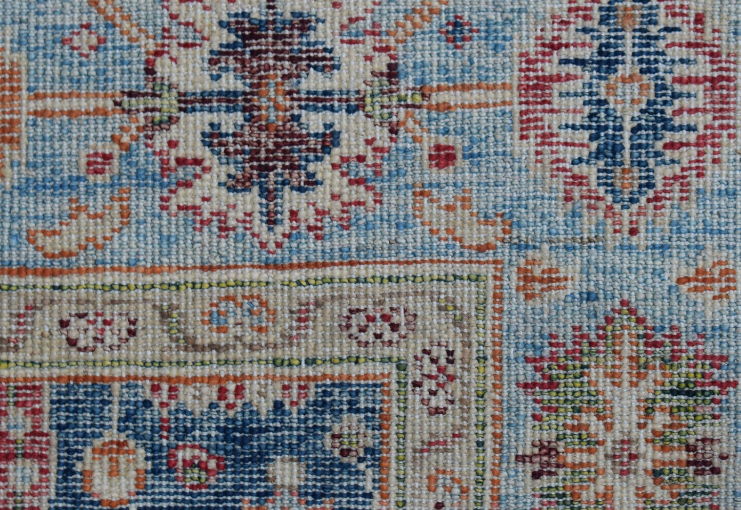 A close-up of a handwoven Afghan Chobi rug featuring intricate geometric patterns in blue and red.