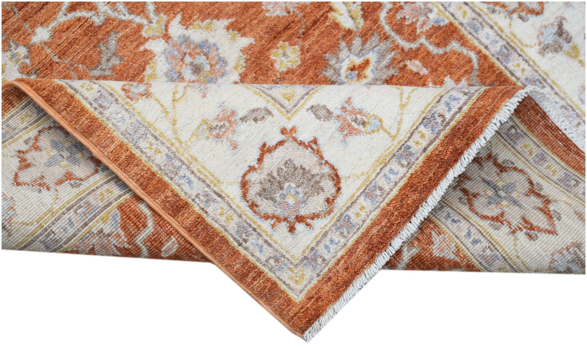 A folded Afghan Chobi rug featuring a traditional floral pattern in rust orange and cream tones.
