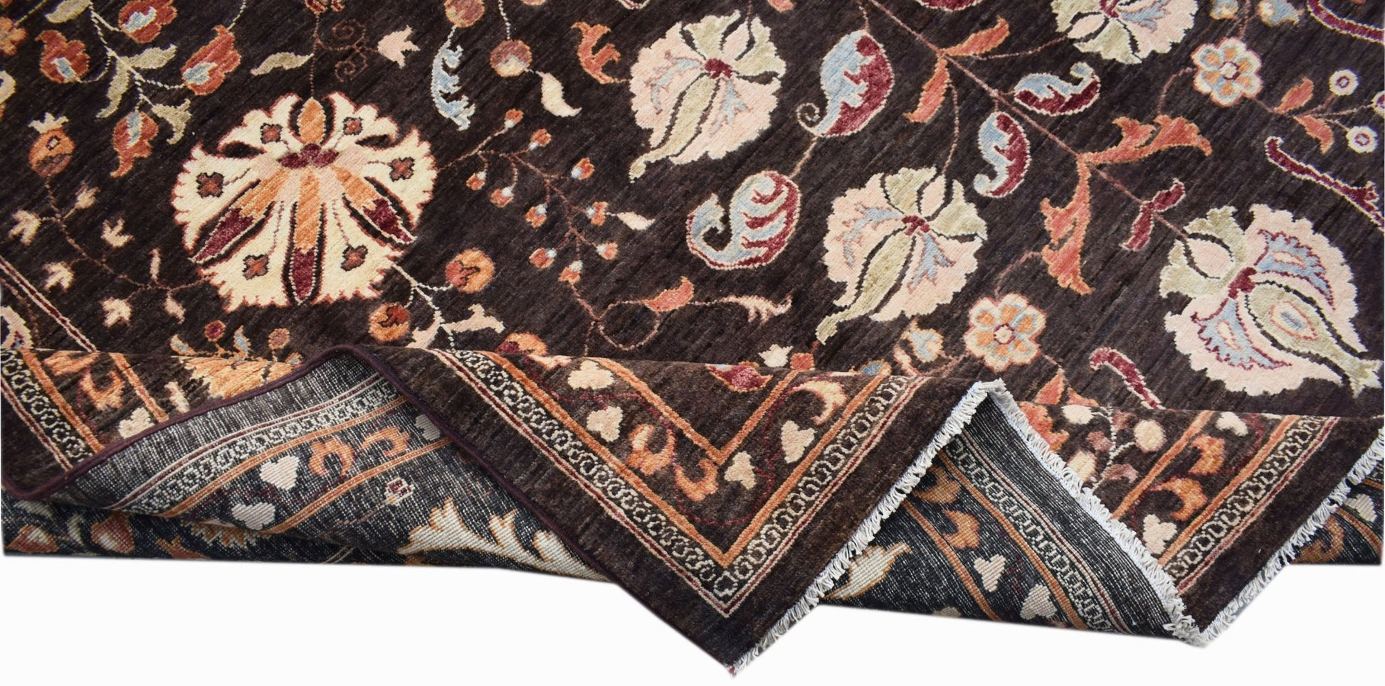 A dark brown Afghan Chobi rug with a floral Suzani pattern and a folded corner.