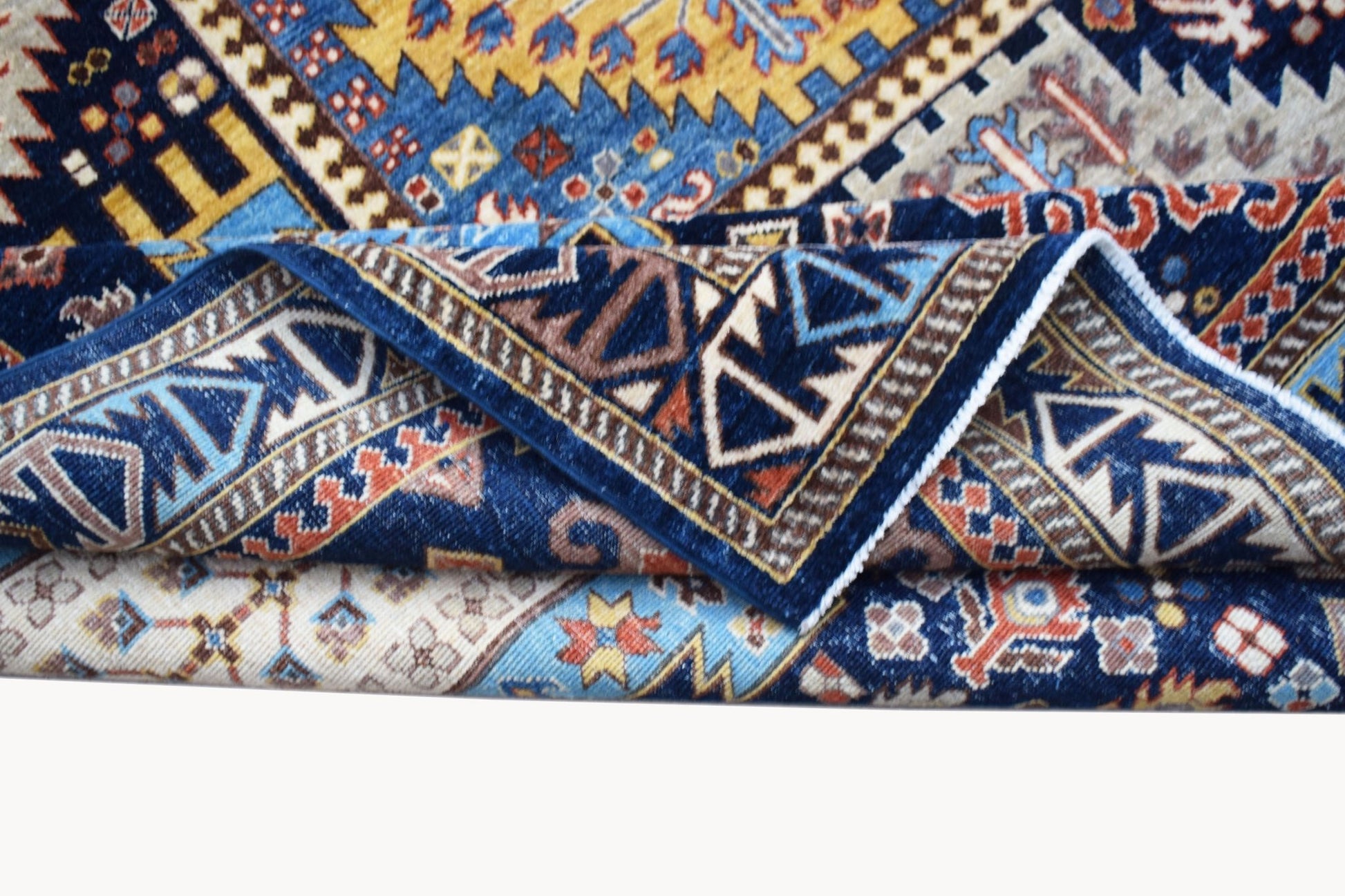 A folded Afghan Chobi rug featuring intricate geometric patterns in blue, yellow, and cream tones.