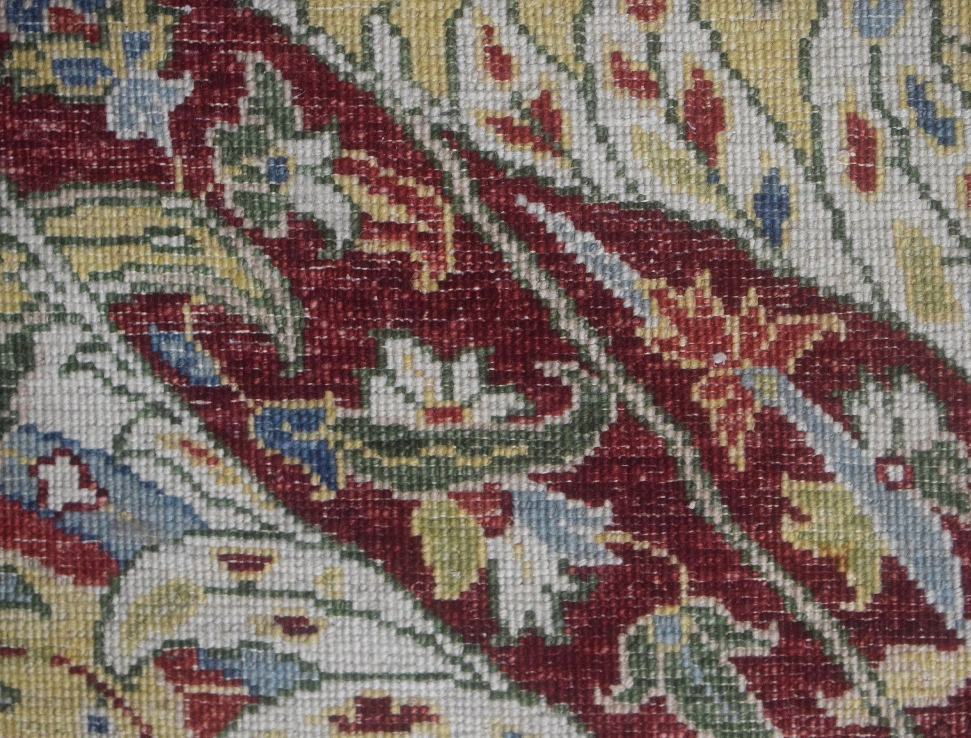 A close-up of a handwoven Afghan Chobi rug featuring intricate floral patterns in red and gold.