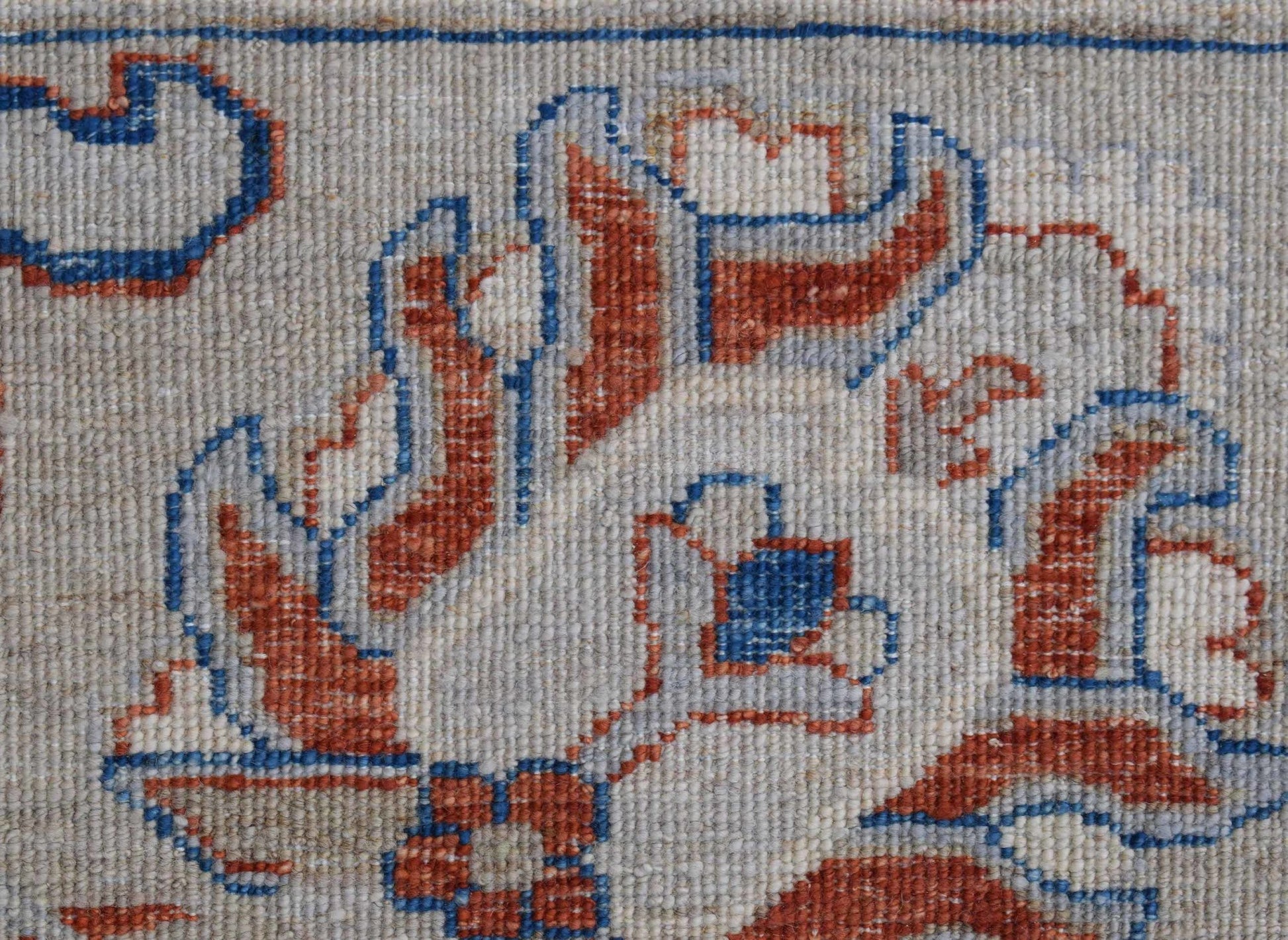 A close-up of an Afghan Chobi rug featuring intricate floral patterns in rust and blue wool.