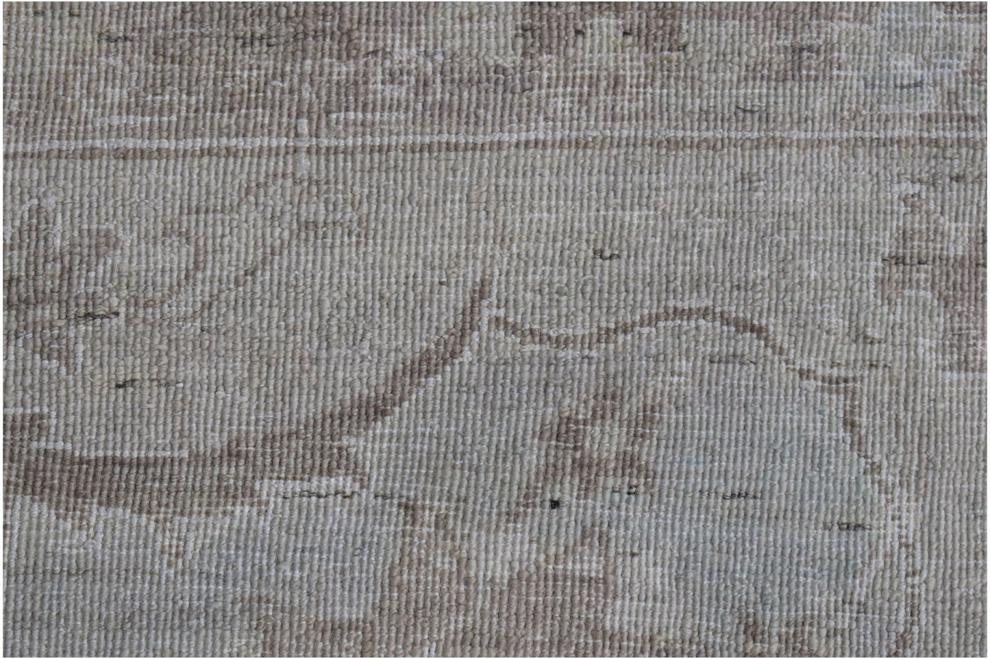 A close-up of a handwoven Afghan Balkh rug featuring a neutral, distressed floral pattern.