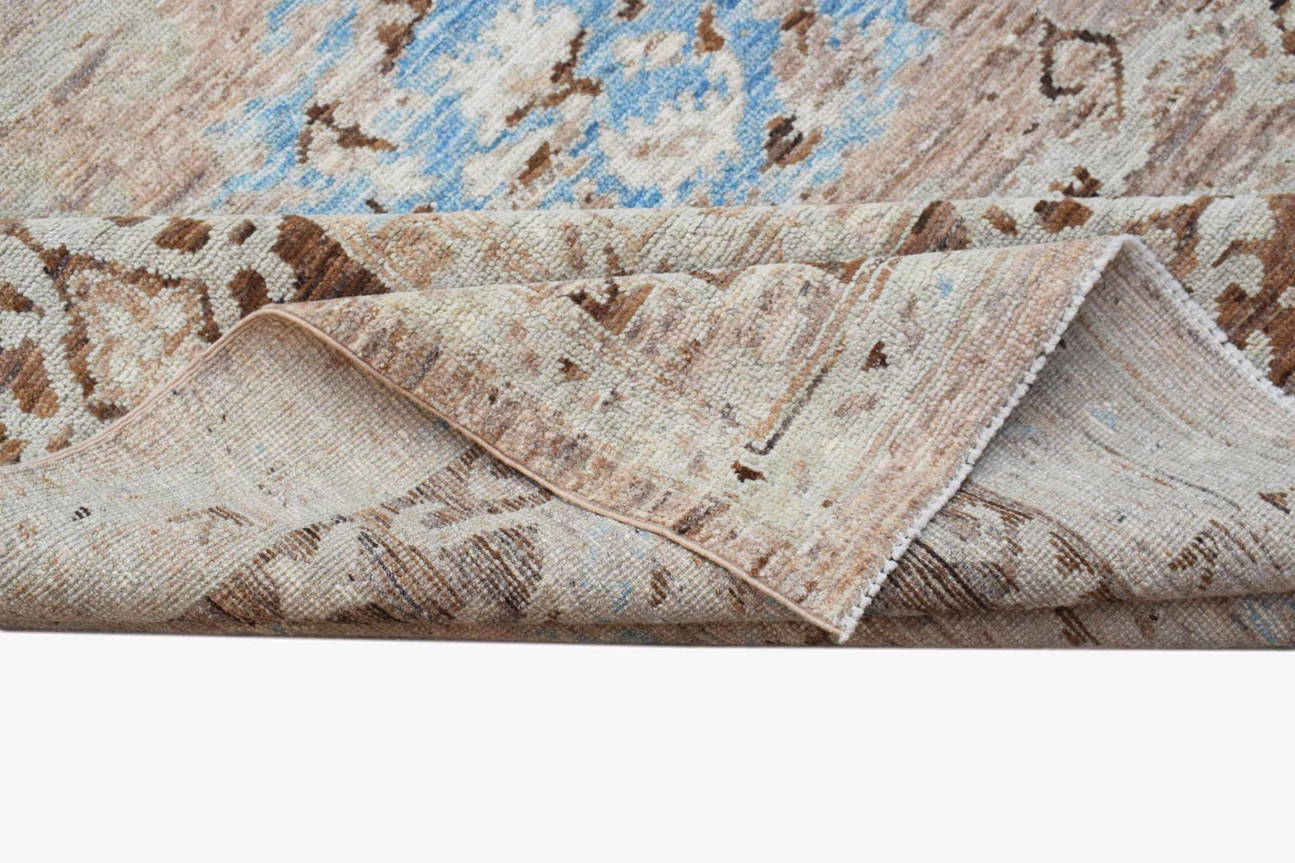 A transitional Oushak rug featuring a distressed floral pattern in blue and beige tones.