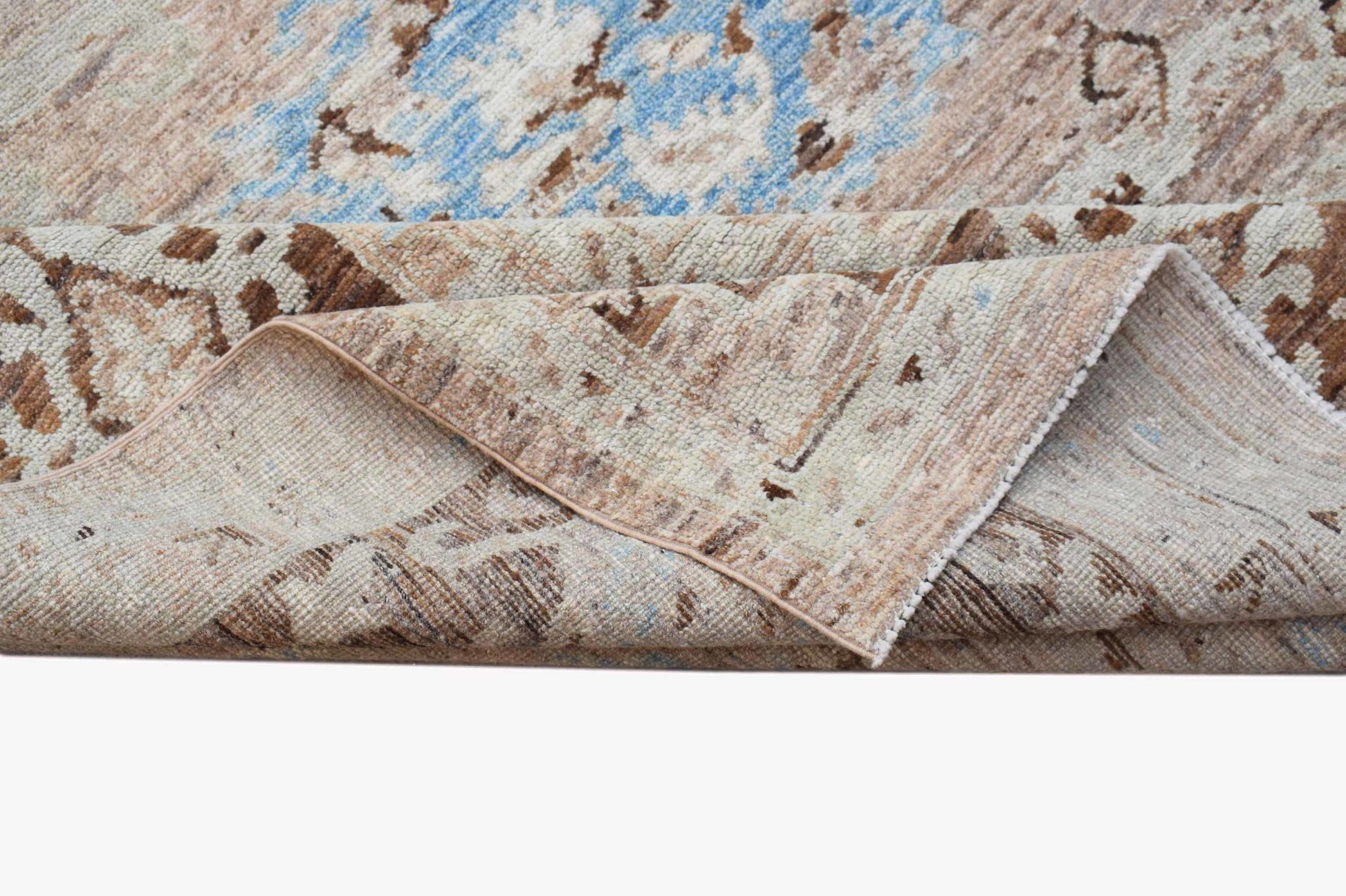 A transitional Oushak rug featuring a distressed floral pattern in blue and beige tones.