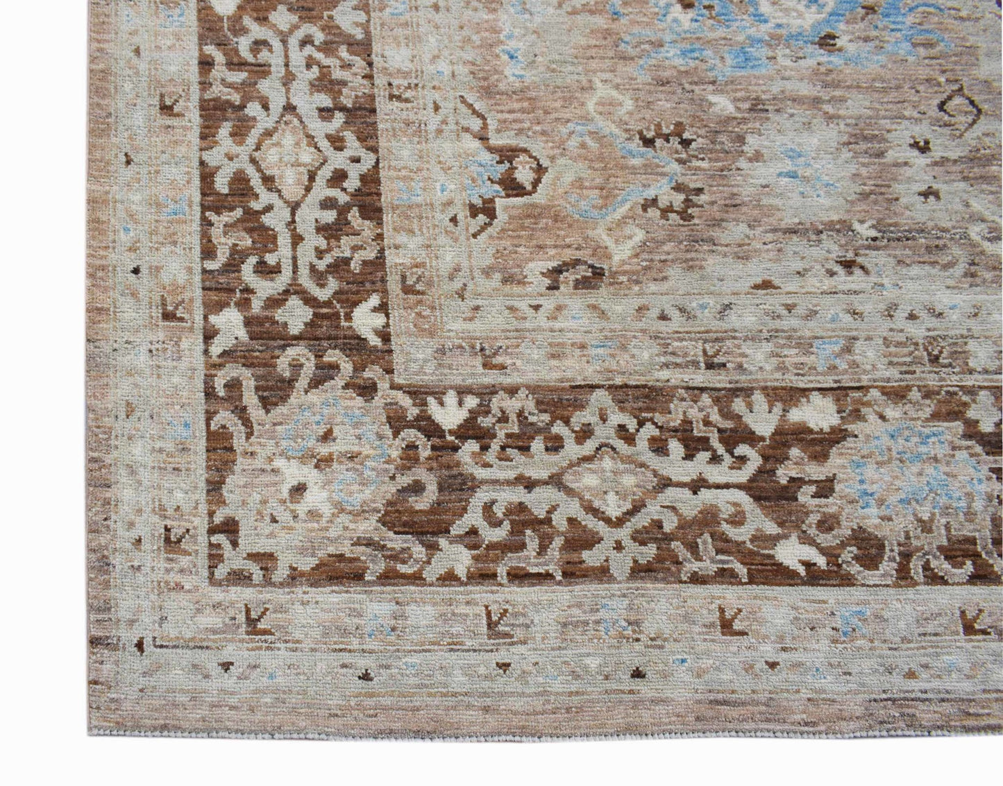 A transitional Oushak rug featuring a brown and beige floral pattern with soft blue accents.