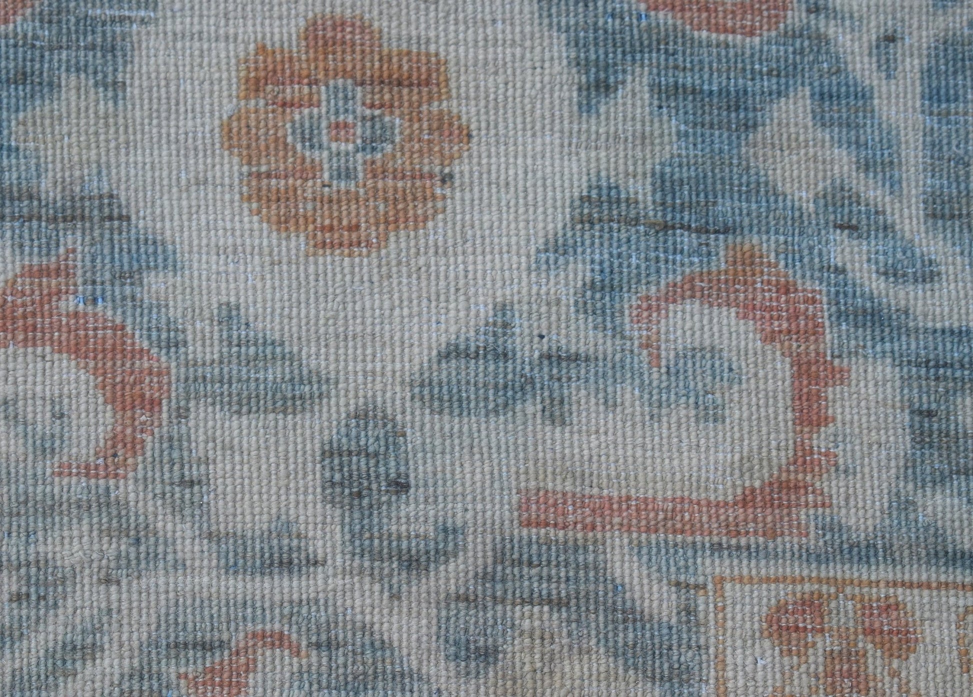 A close-up of a handwoven Afghan Balkh rug featuring traditional floral patterns in muted tones.