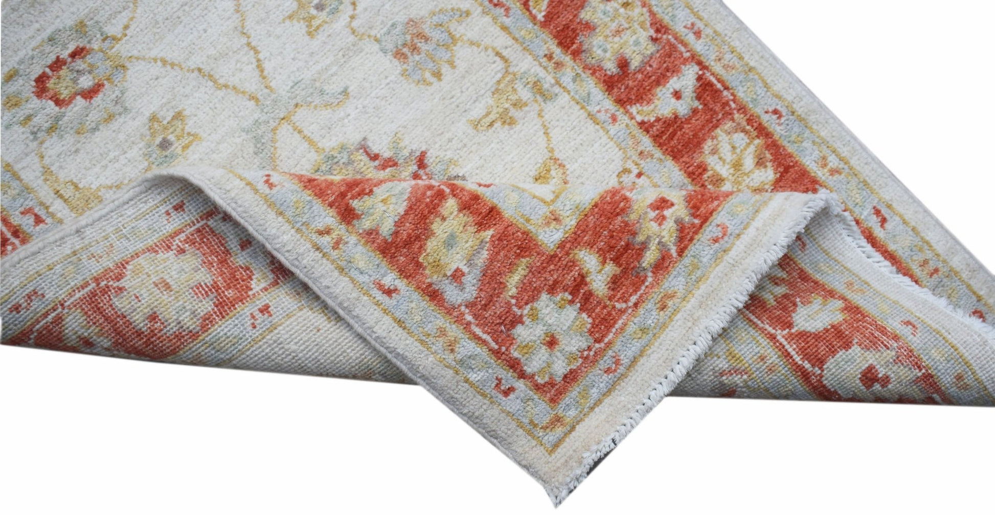 An Afghan Chobi runner with a cream field and a floral red border, shown folded to reveal its back.