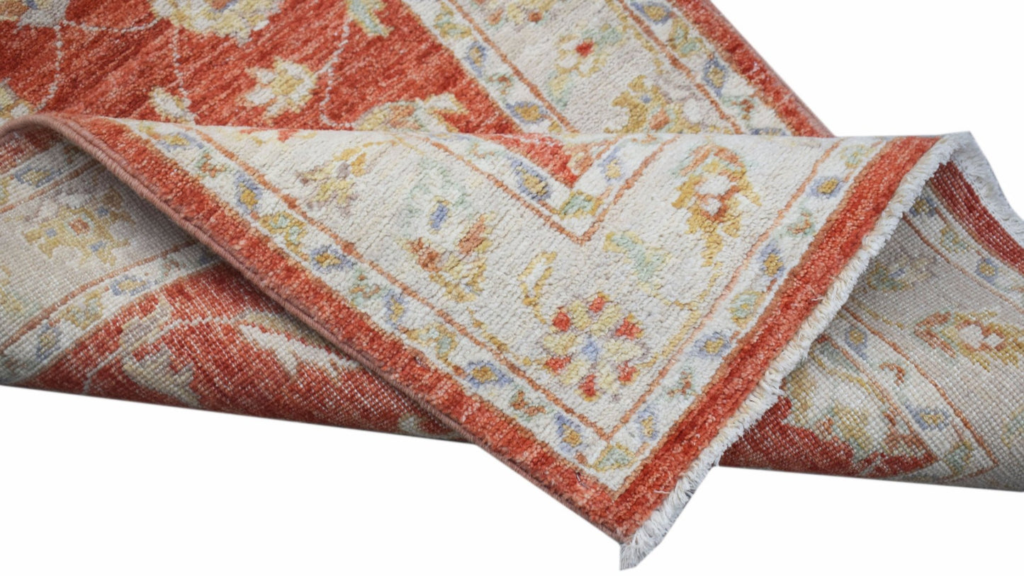A handwoven Afghan Chobi runner featuring a traditional floral pattern in rust and cream tones.