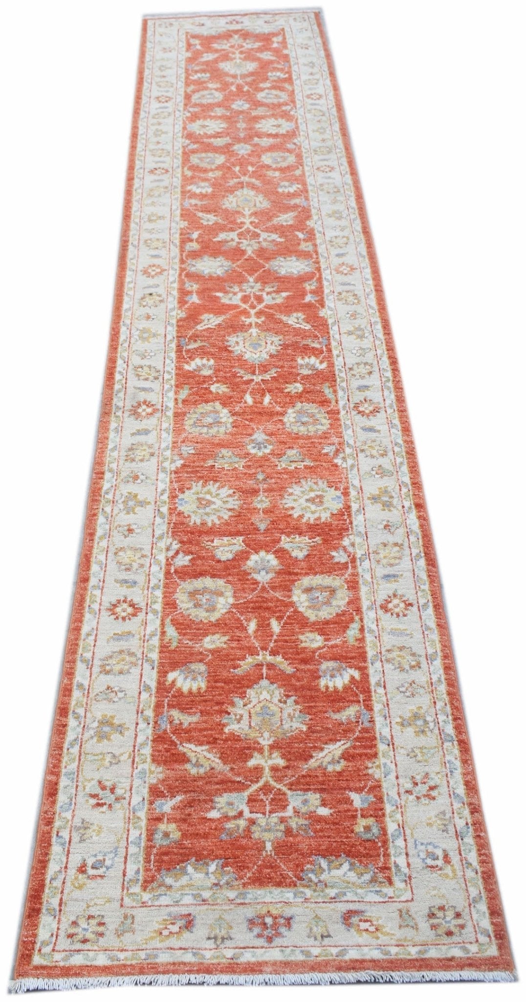 An Afghan Chobi runner rug featuring a traditional floral pattern in shades of orange and cream.