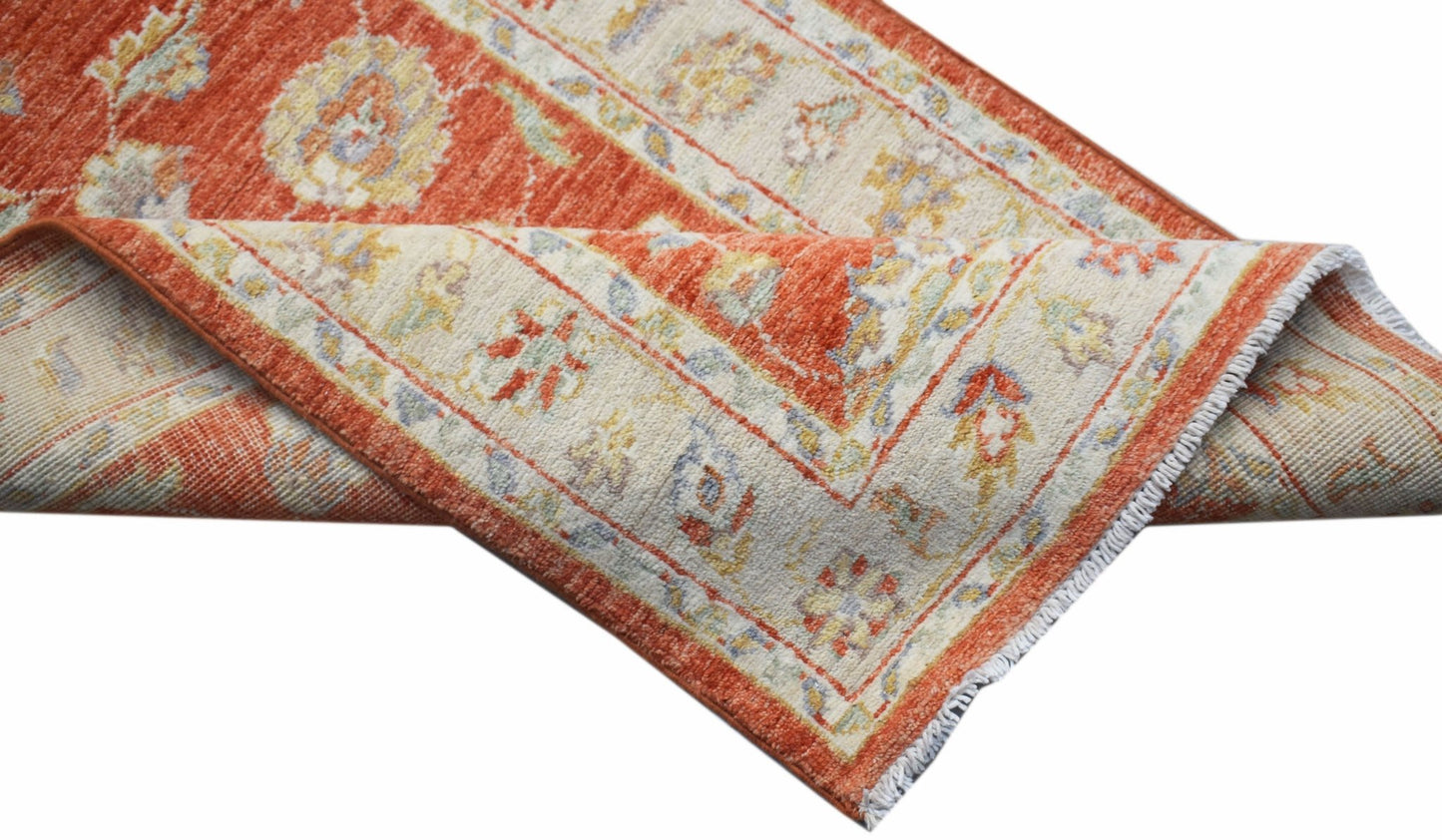A handmade Afghan Chobi runner featuring a traditional floral pattern in orange and cream tones.