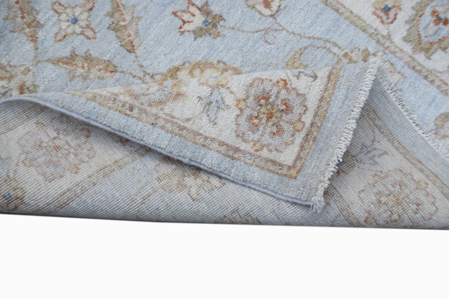 A handwoven Afghan Chobi runner featuring a light blue field with traditional floral patterns.