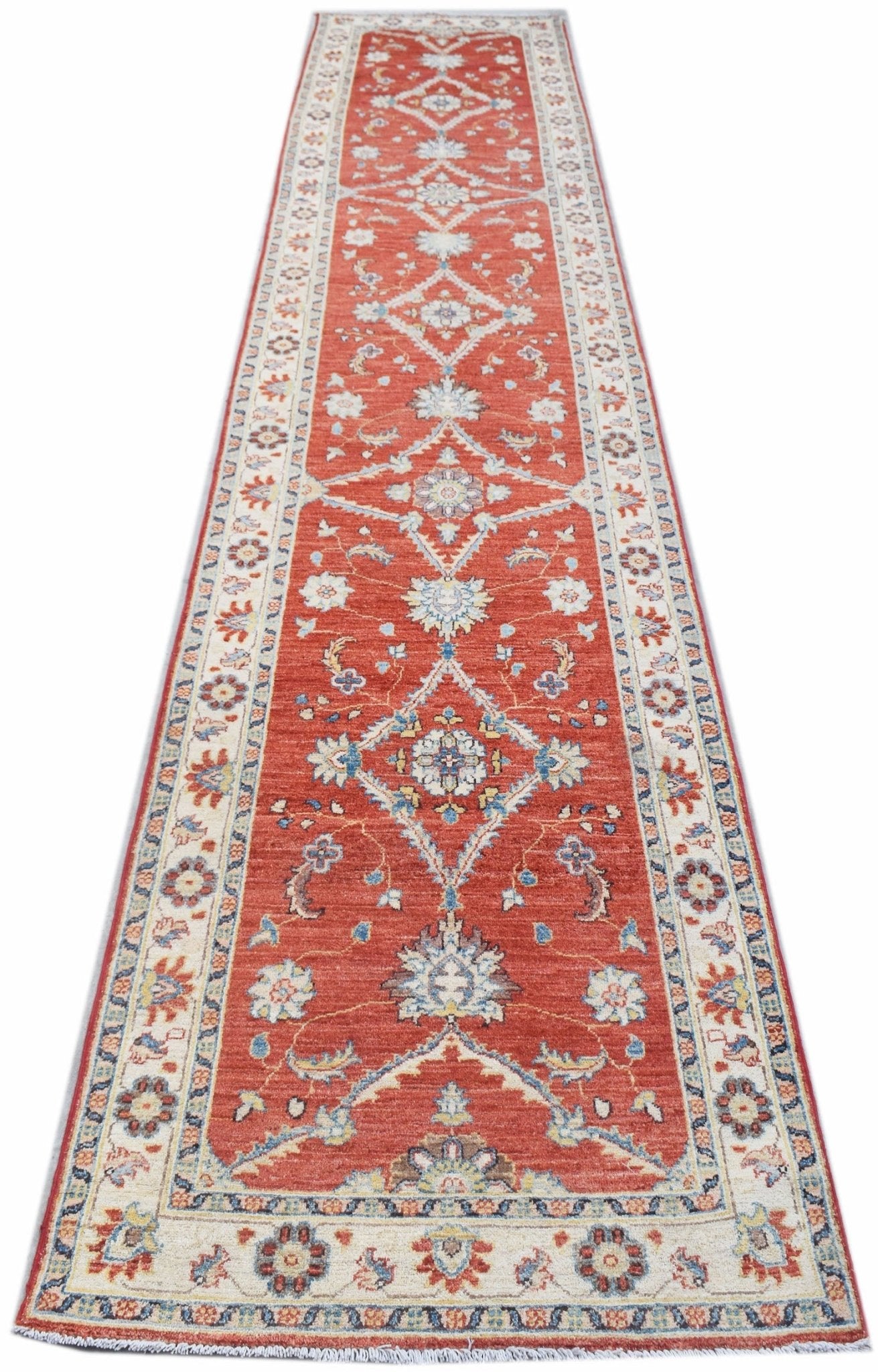 A handmade Afghan Chobi runner rug featuring a traditional floral pattern in red and cream tones.