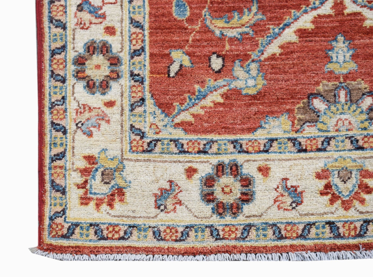 A corner view of a handwoven Afghan Chobi runner featuring traditional floral patterns in red.