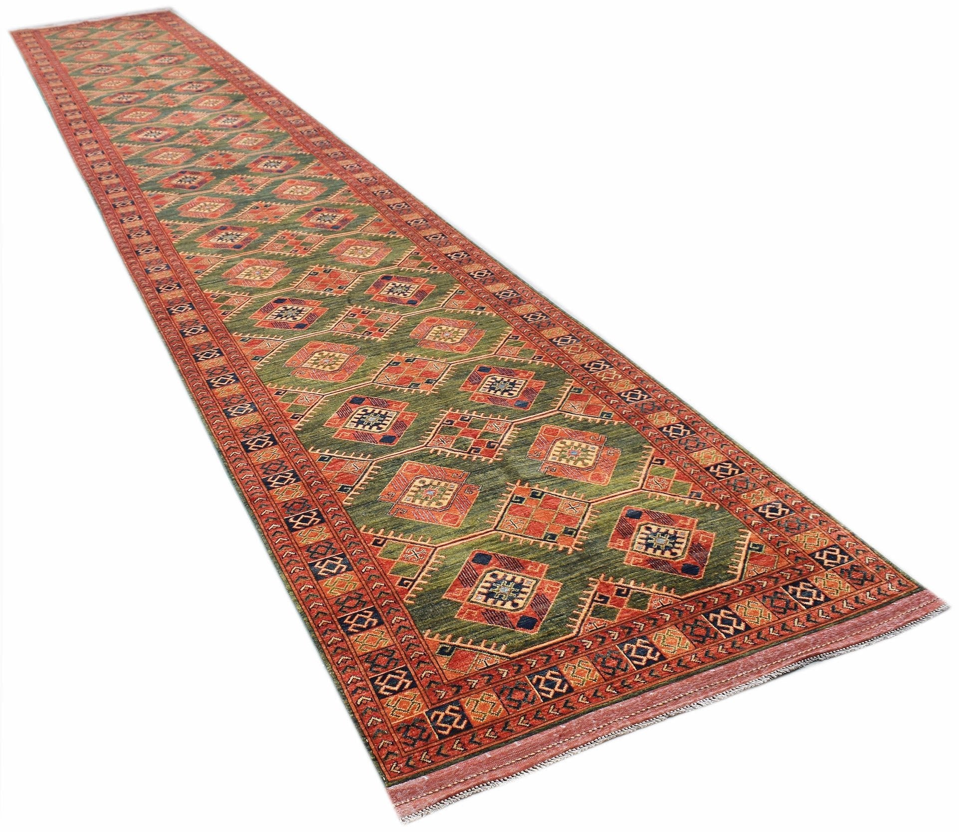 An Afghan Chobi runner rug featuring a repeating diamond pattern in earthy tones on a green field.