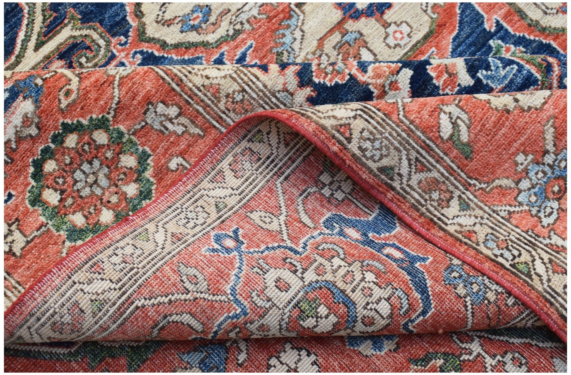 A folded Afghan Chobi rug featuring a traditional Heriz pattern in red, blue, and cream tones.