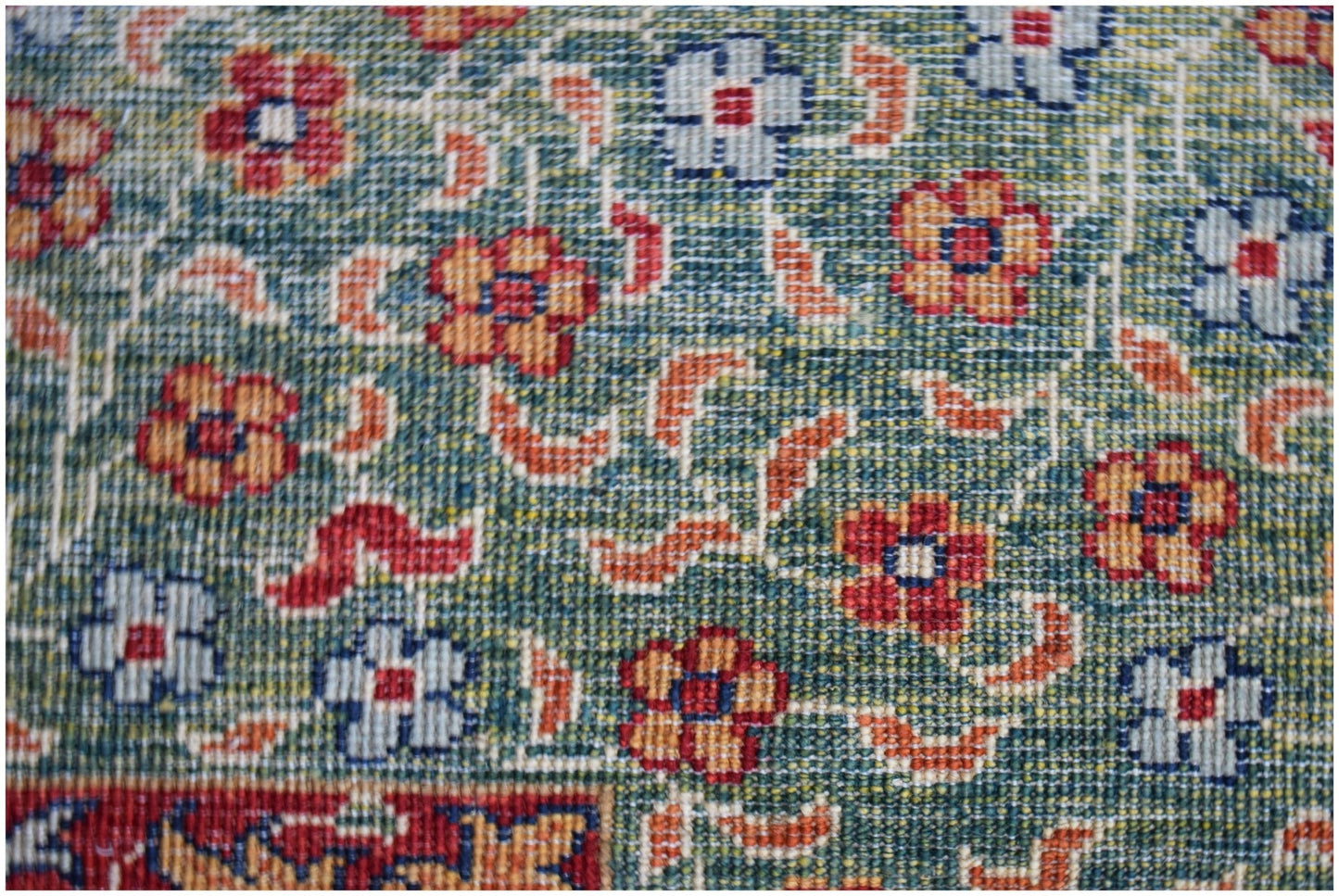 A close-up of a handwoven Afghan Chobi rug featuring a floral pattern in blue, red, and orange.