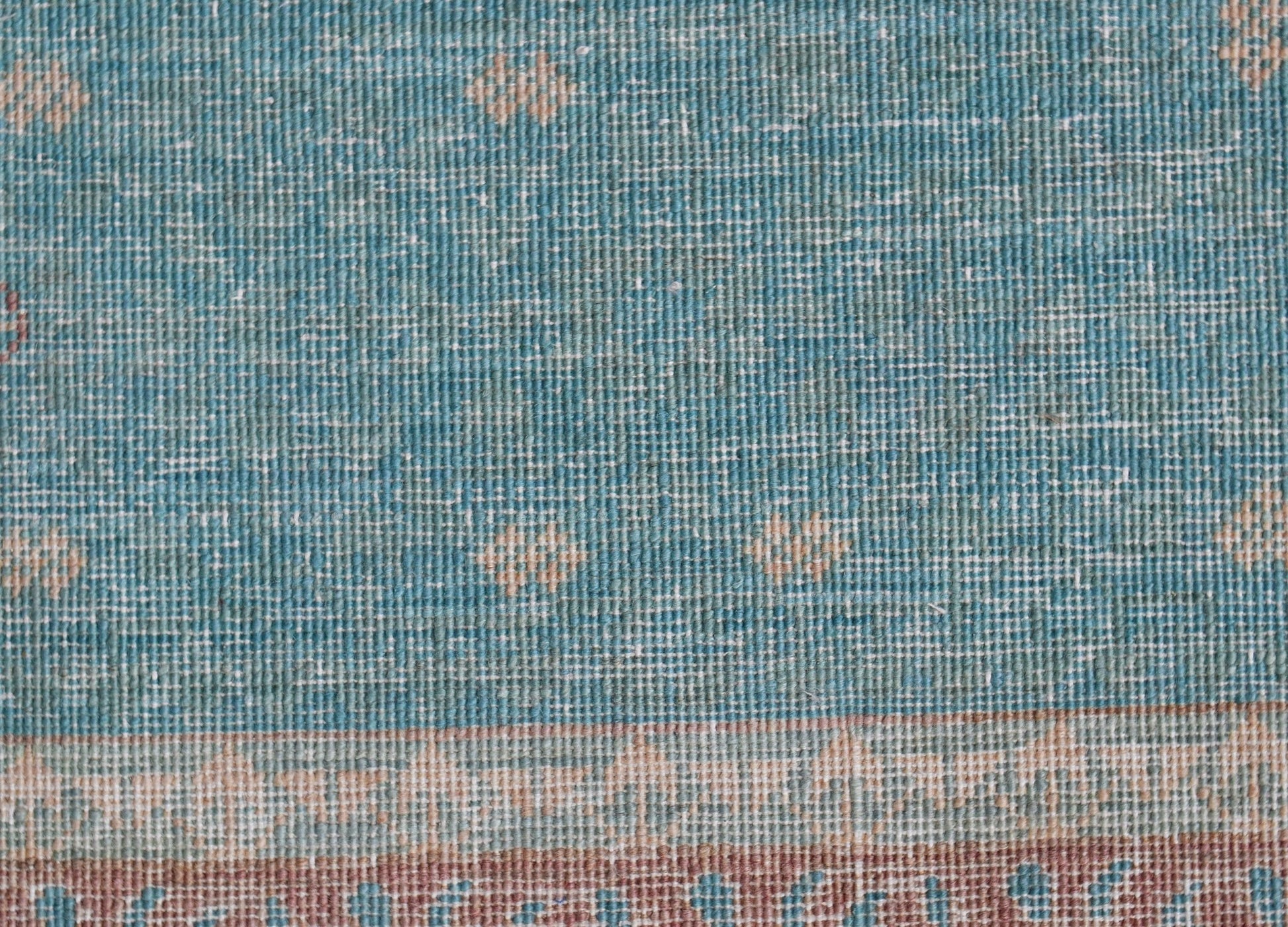 A close-up of a handwoven Afghan Balkh rug featuring a blue field with subtle geometric patterns.