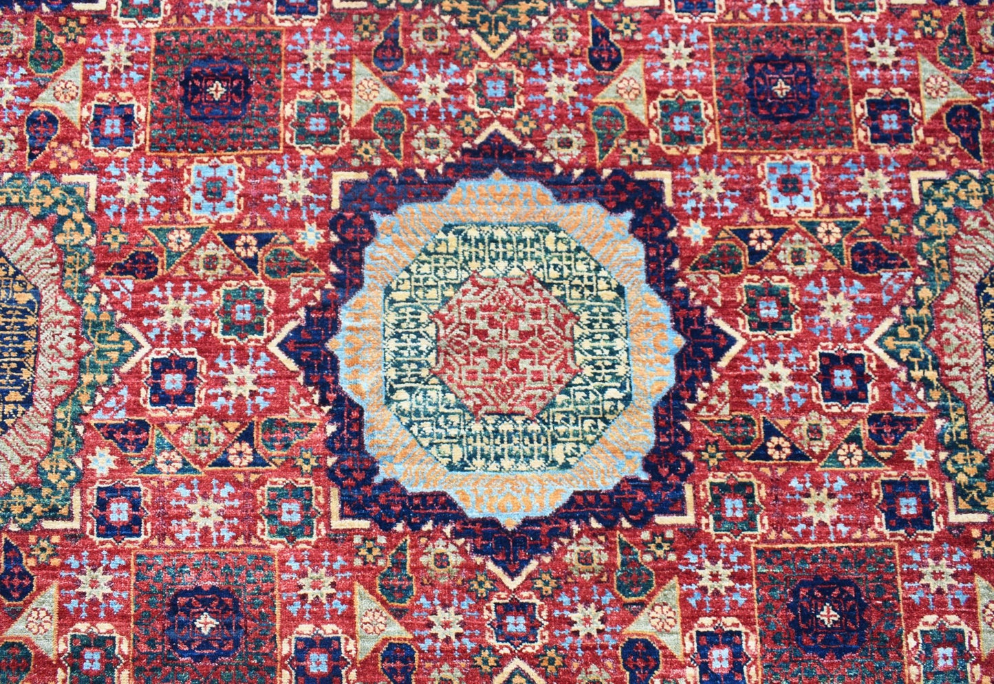 A handmade Afghan Chobi rug featuring a detailed Mamluk medallion pattern in red, blue, and gold.