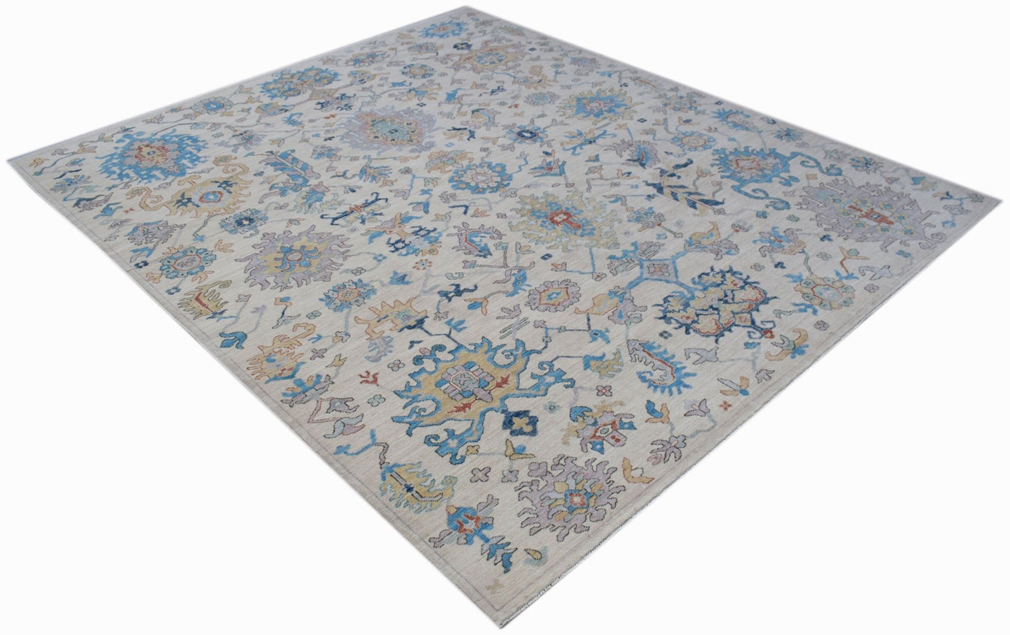 An Afghan Chobi rug featuring a traditional floral pattern in blue, gold, and grey on a cream base.