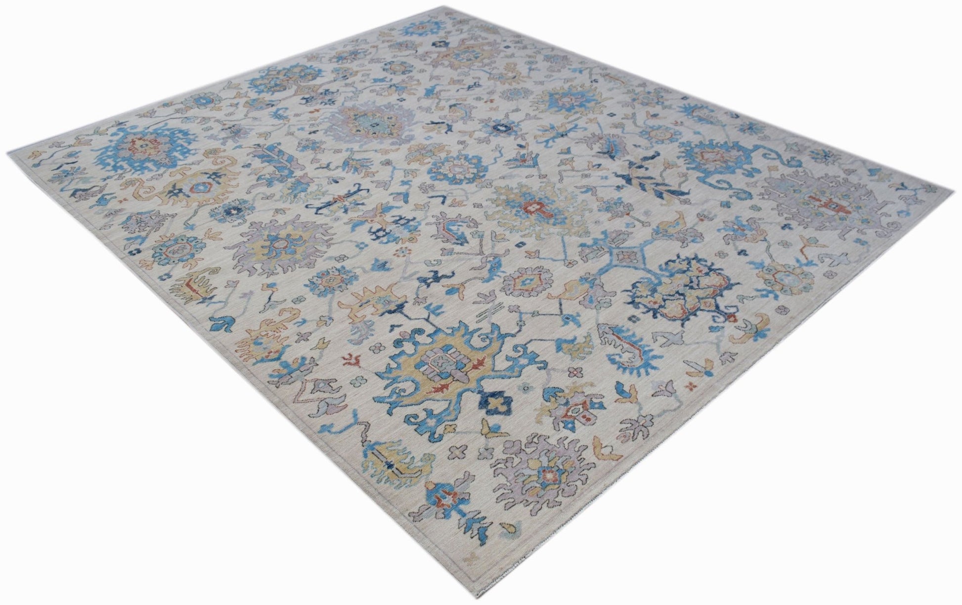 An Afghan Chobi rug featuring a traditional floral pattern in blue, gold, and grey on a cream base.