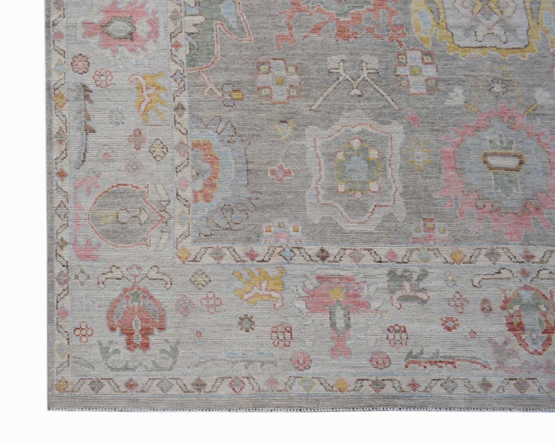 A handwoven transitional Oushak rug featuring a floral pattern in soft pastel tones on a grey base.