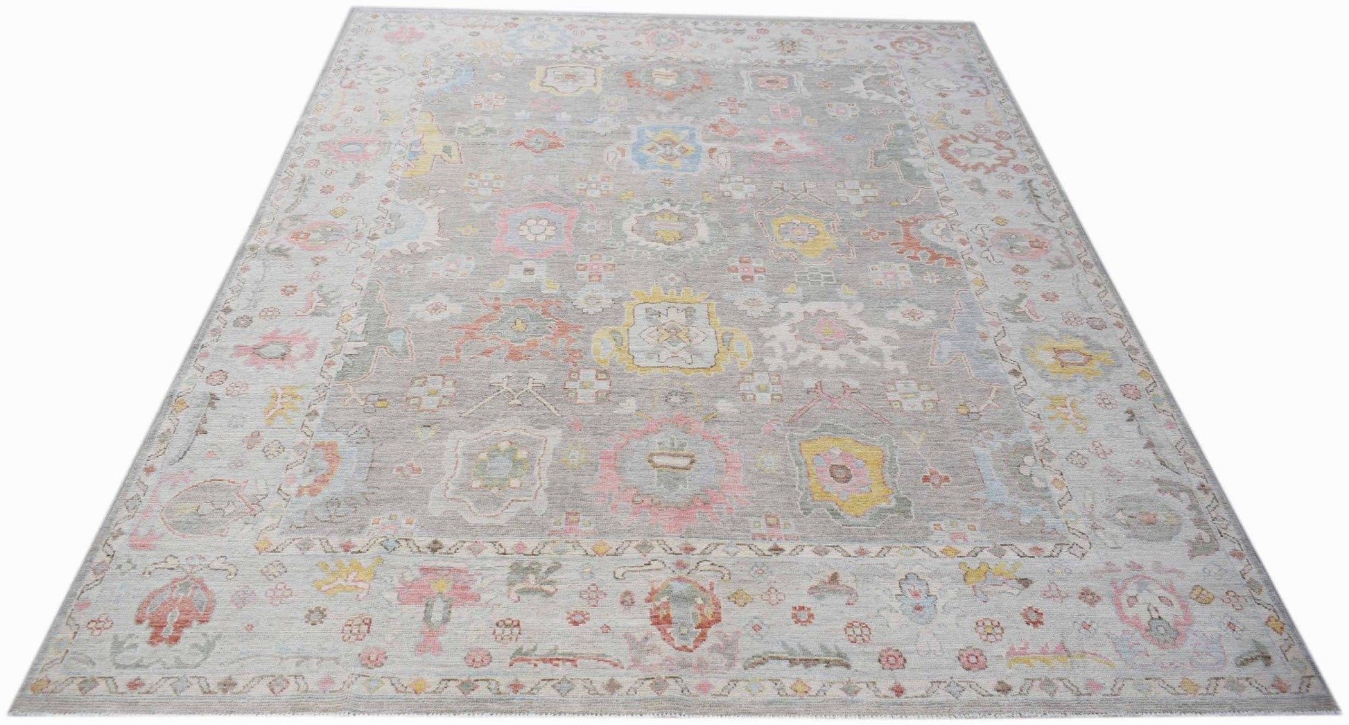A handmade transitional Oushak rug featuring a light grey field with colorful floral motifs.