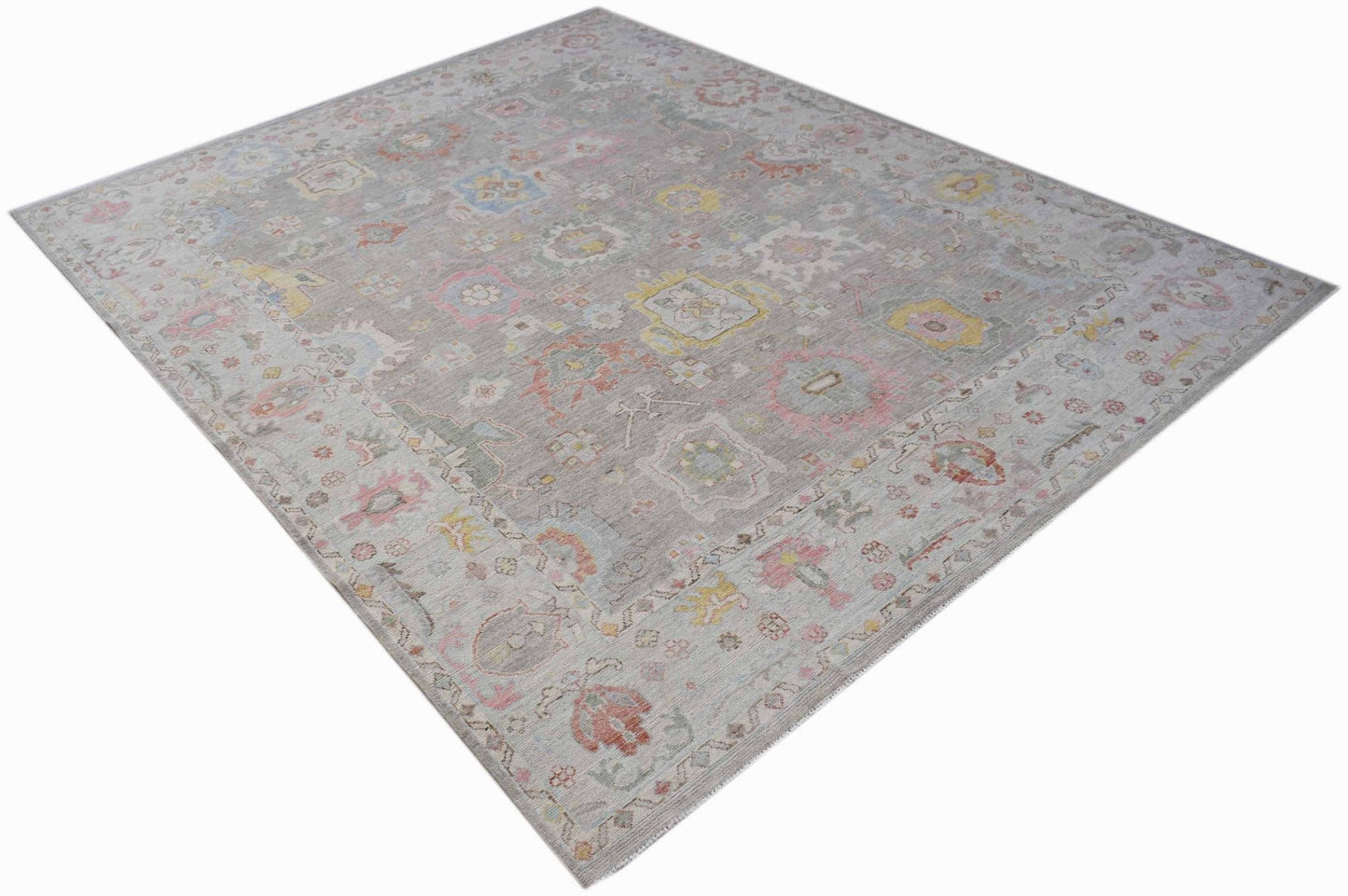 A rectangular transitional Oushak rug featuring a grey field with colorful floral motifs.