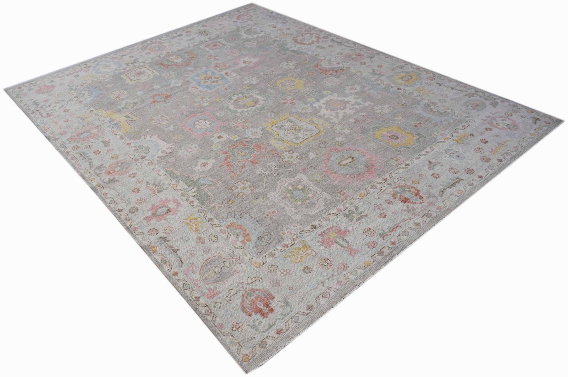 A rectangular transitional Oushak rug featuring a grey field with colorful floral motifs.