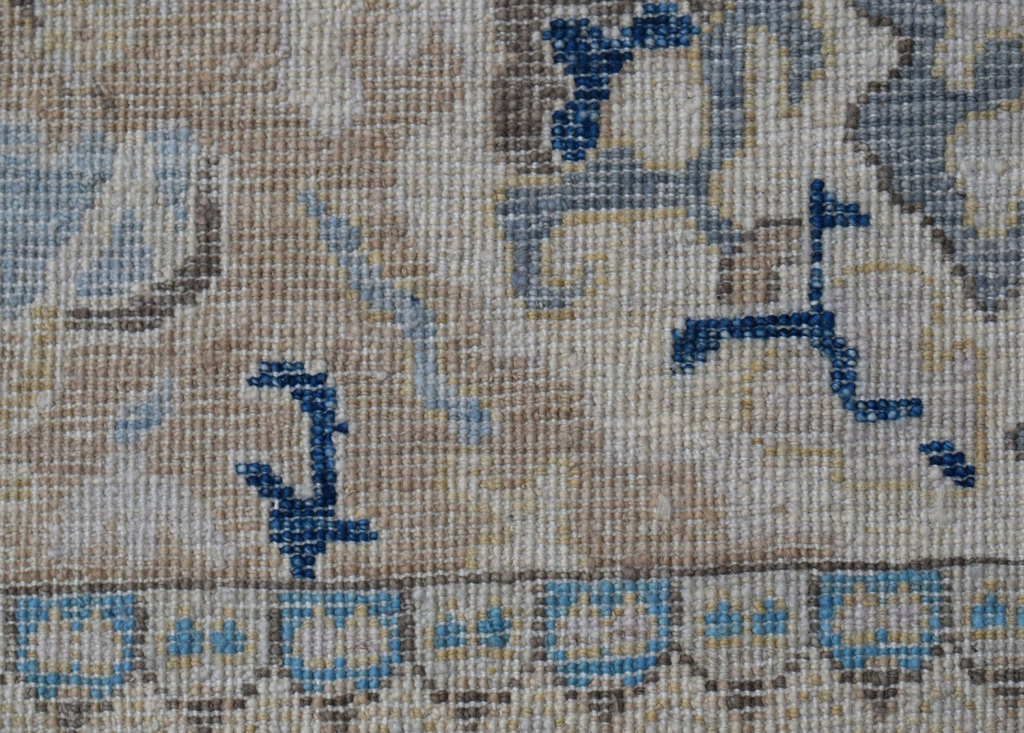 A close-up of a handwoven Afghan Chobi rug featuring intricate blue and beige floral patterns.