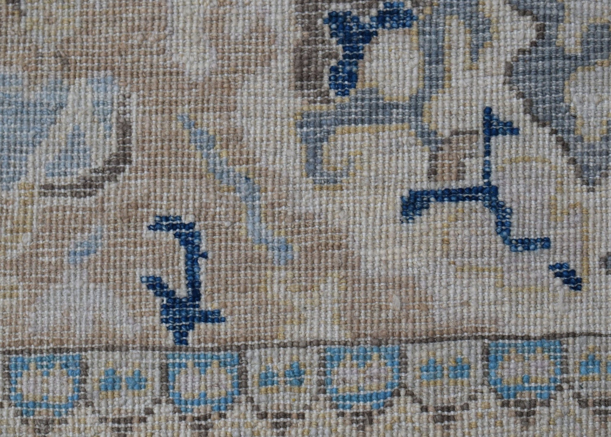 A close-up of a handwoven Afghan Chobi rug featuring intricate blue and beige floral patterns.