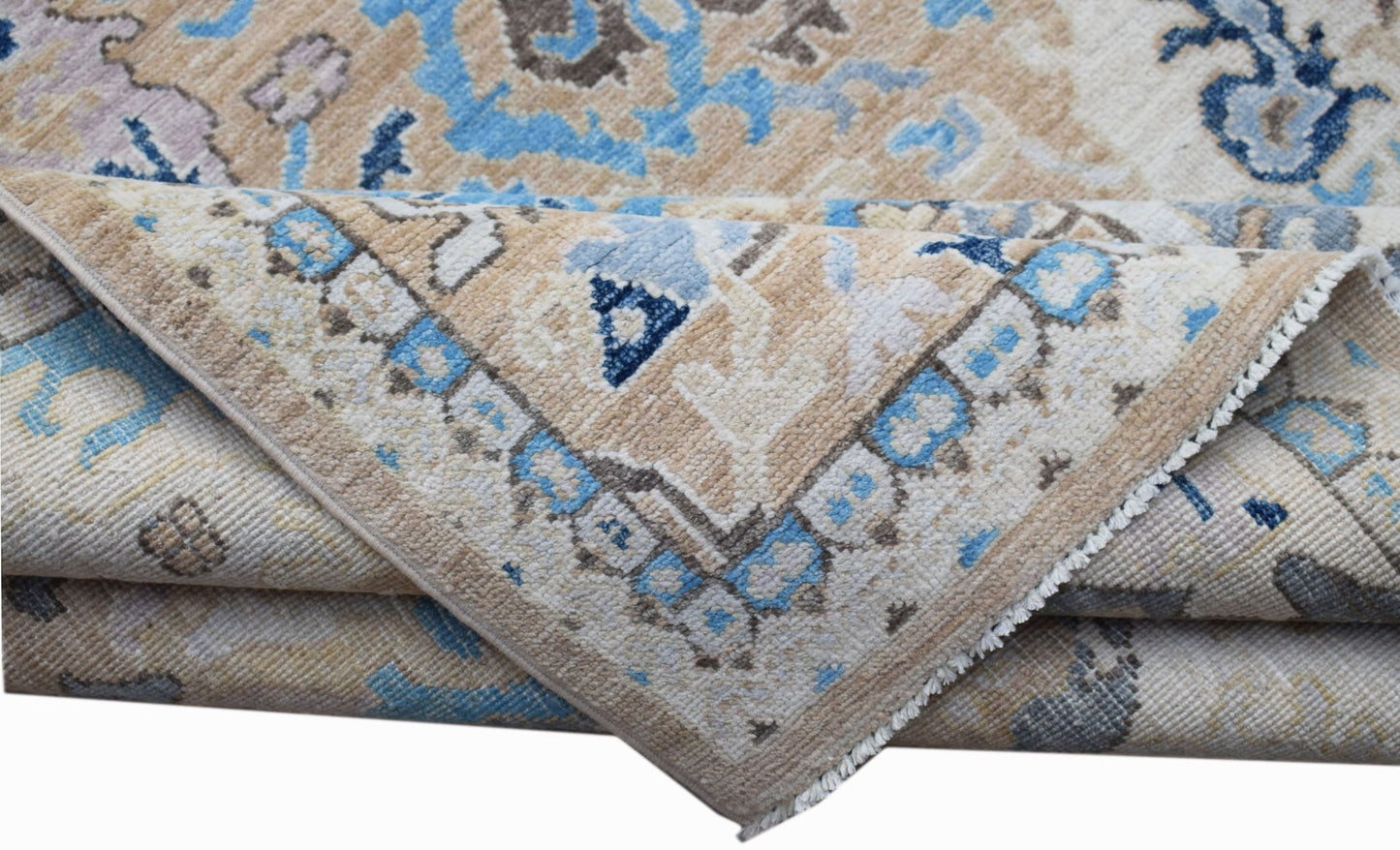 A folded Afghan Chobi rug featuring a traditional floral pattern in shades of blue and beige.
