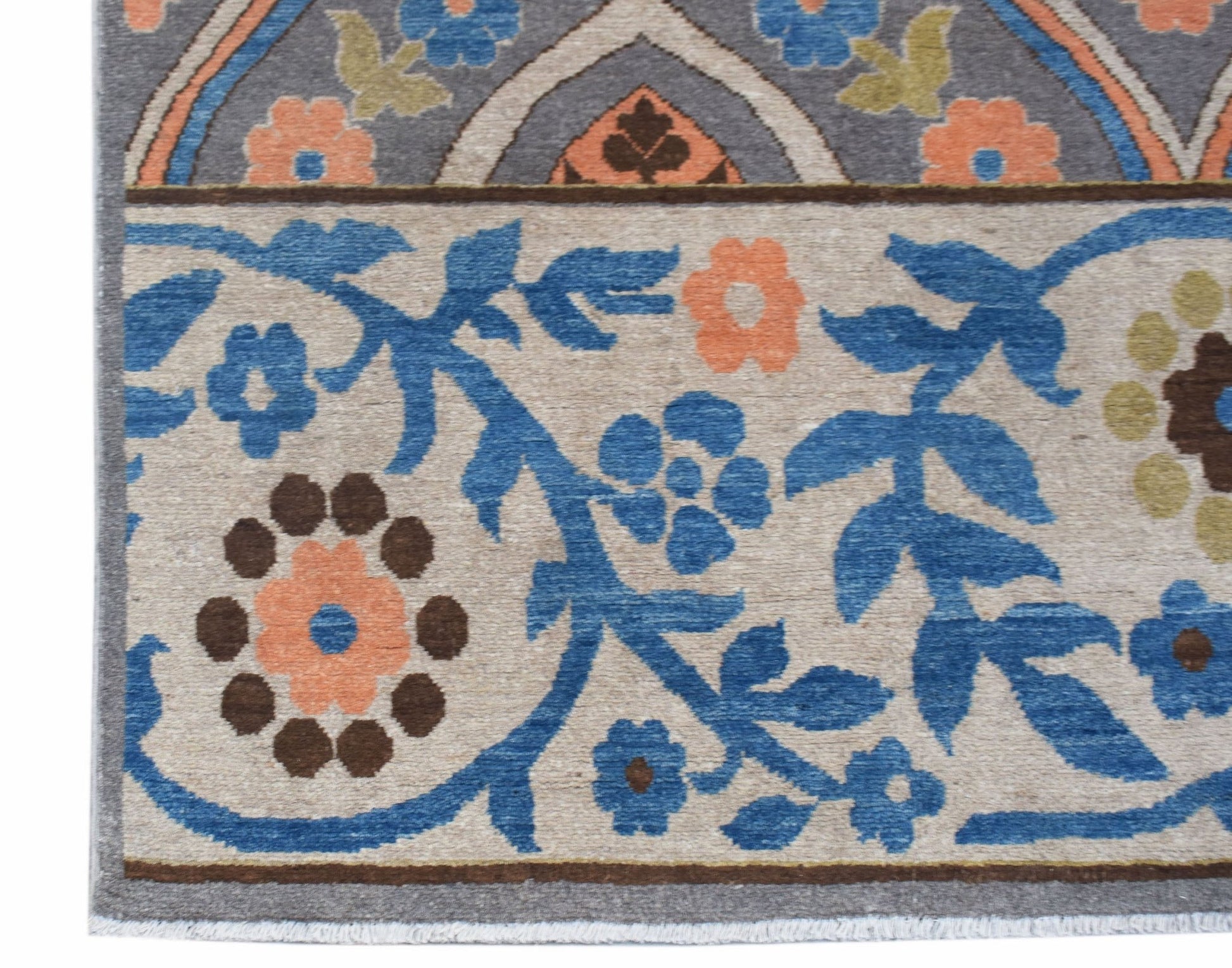 A close-up of an Afghan Chobi rug featuring a floral pattern in blue, orange, and brown on beige.
