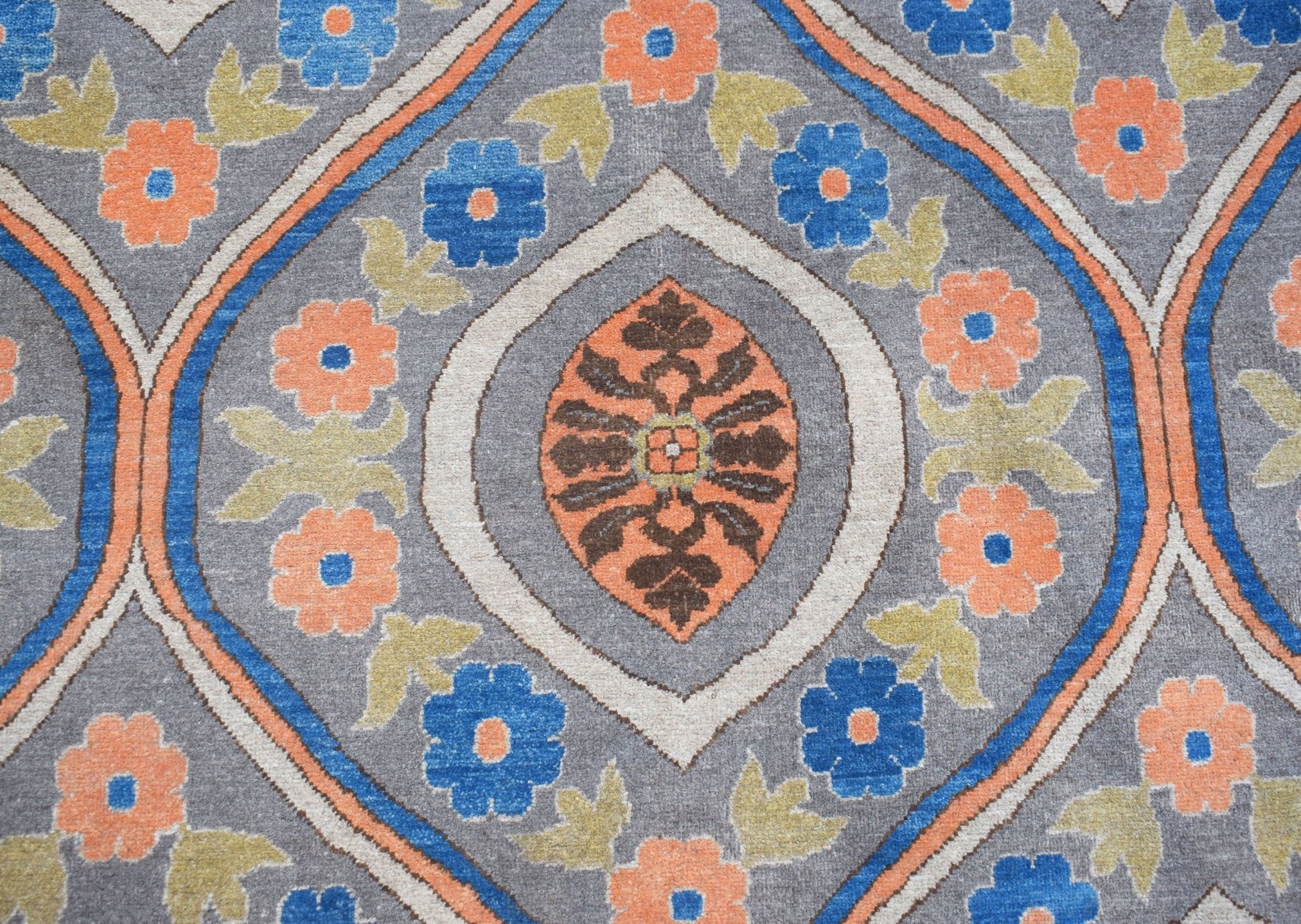 Handwoven Afghan Chobi rug featuring a grey background with orange and blue floral patterns.