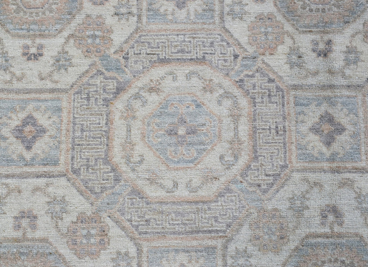 A handmade Afghan Chobi rug featuring a traditional geometric pattern in soft blue and beige tones.