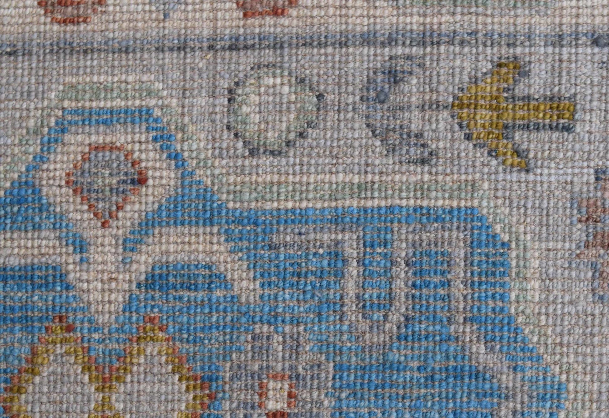 A close-up view of a handwoven Afghan Chobi rug featuring intricate blue and earthy geometric motifs.
